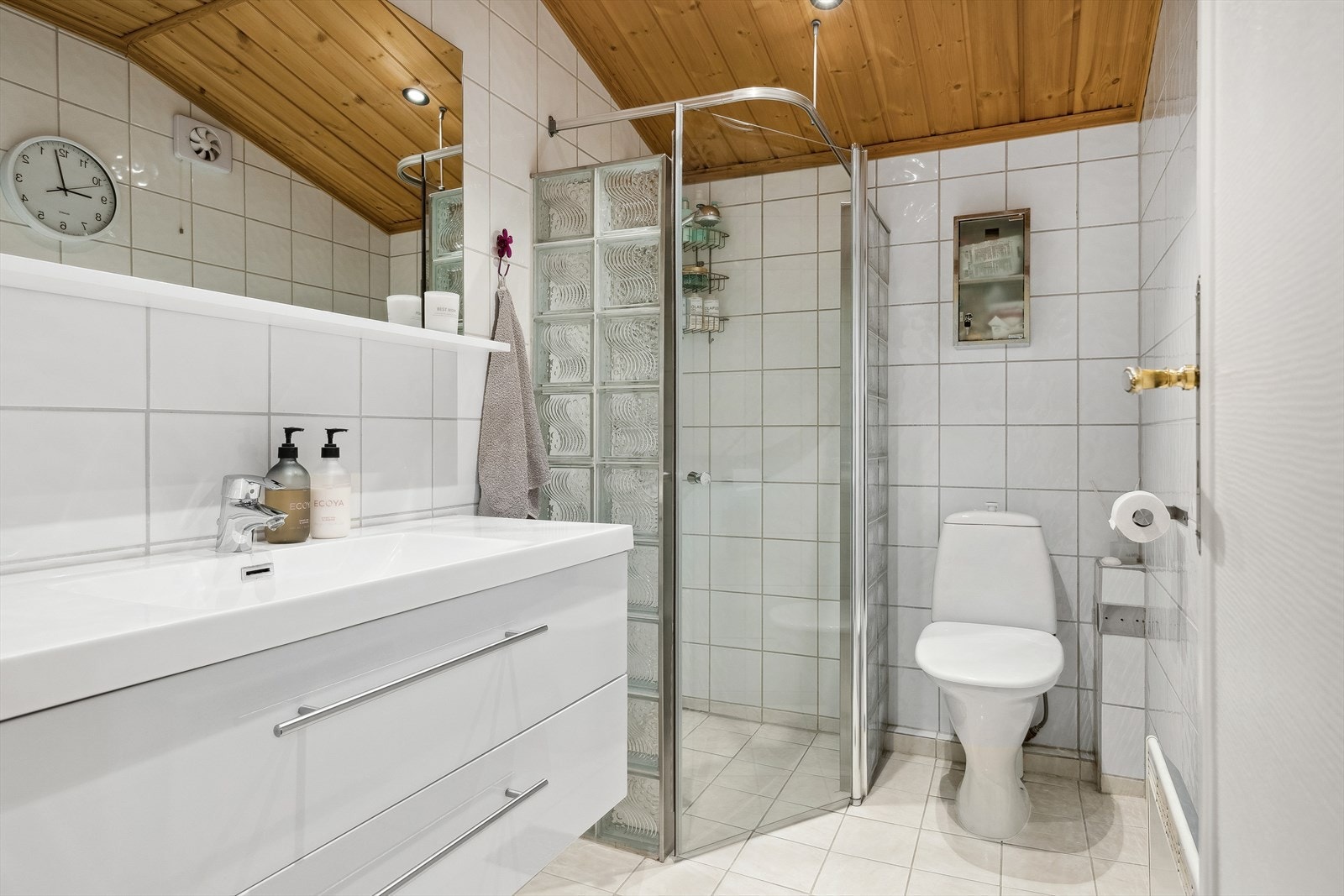 Flislagt bad som er innredet med wc, dusjhjørne og baderomsinnredning med heldekkende servant. Galleribilde