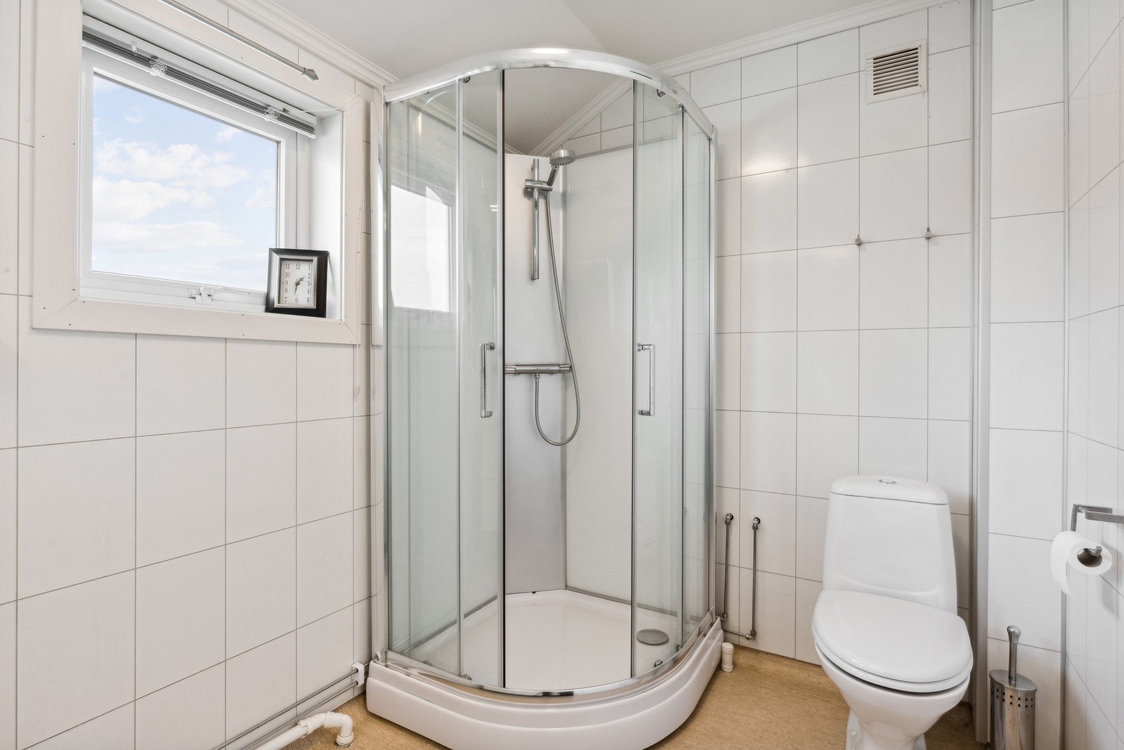Badet har innredning med heldekkende servant og skuffer, høyskap, dusjkabinett og frittstående toalett Galleribilde