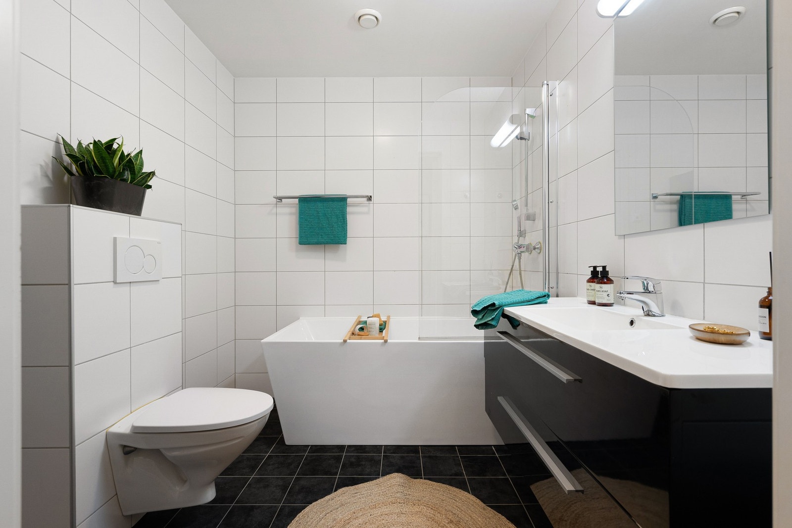 Badet i 1. etasje er innredet med badekar, mekanisk avtrekk, veggmontert toalett og servant i skap. Galleribilde