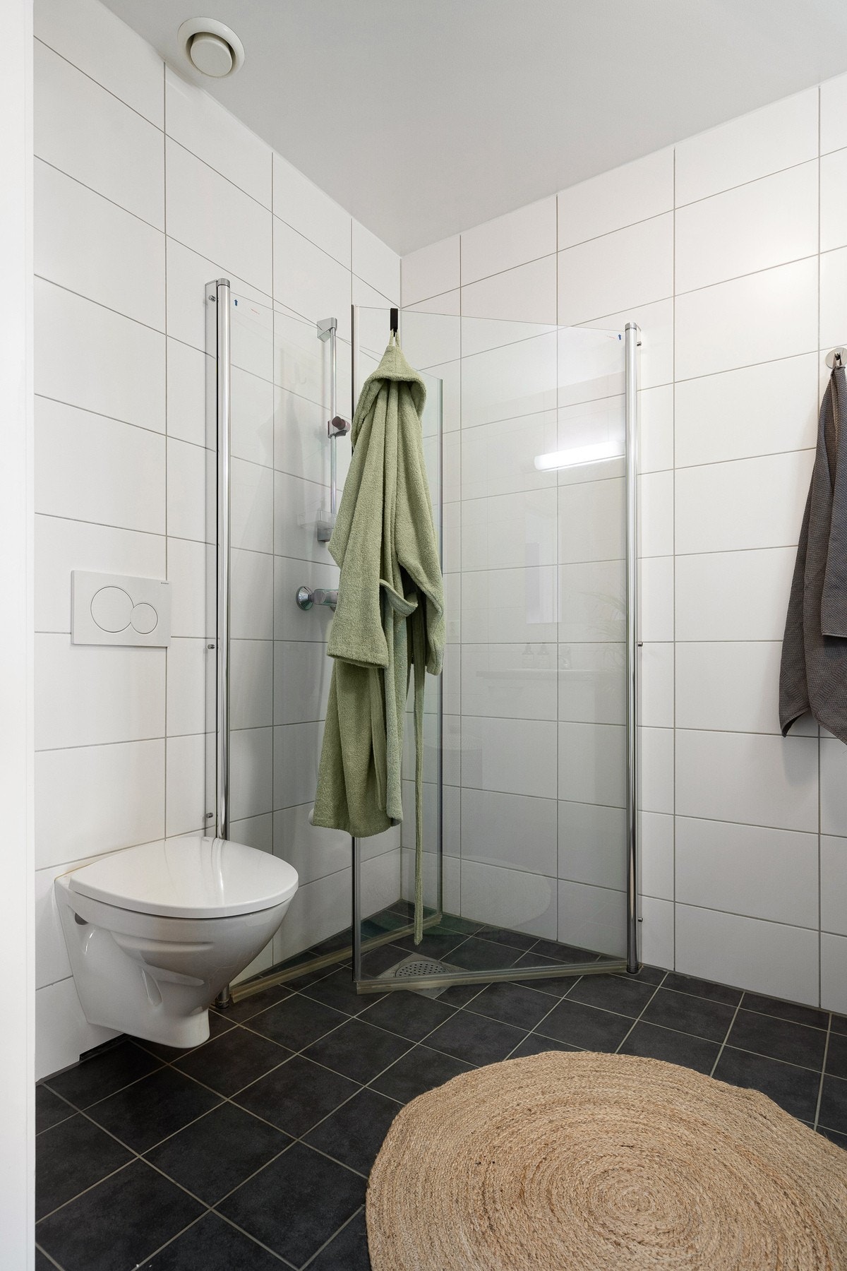 Badet er innredet med innfellbare dusjdører, mekanisk avtrekk, veggmontert toalett og servant i skap. Galleribilde