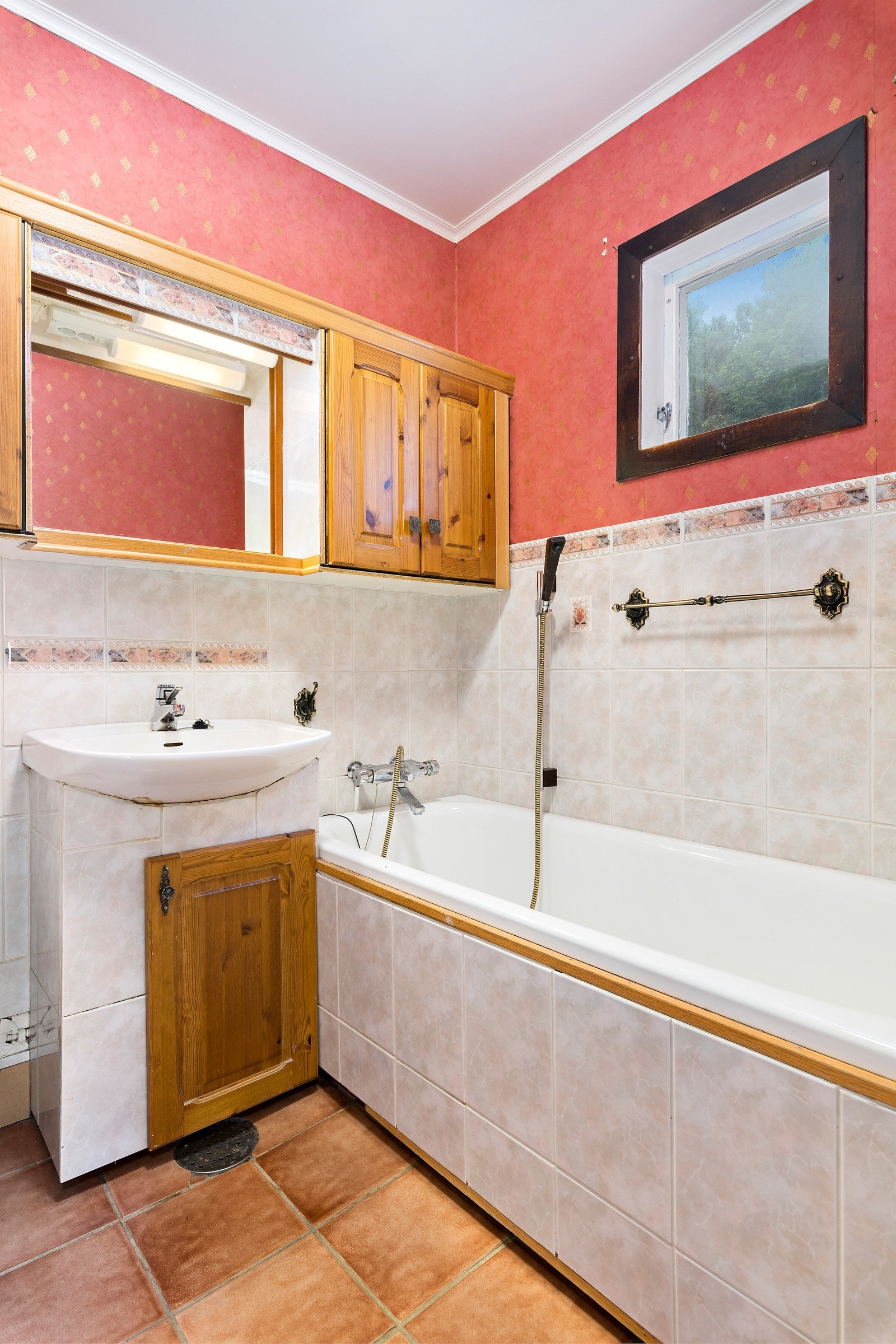 Badet har fliser på gulvet. Det er innredet med servant på veggen, badekar og gulvmontert wc. Galleribilde