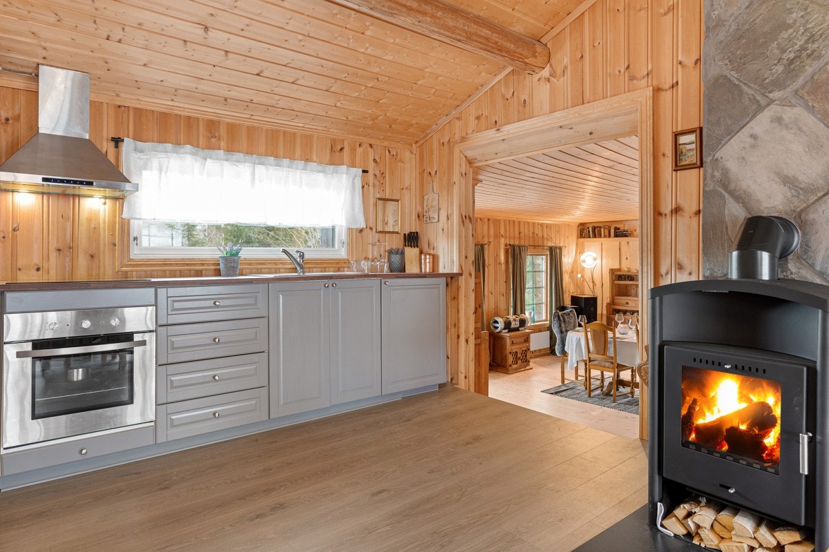 Kjøkkeninnredning med intergrerte stekeovn og koketopp. Vedovn på kjøkkenet. Galleribilde