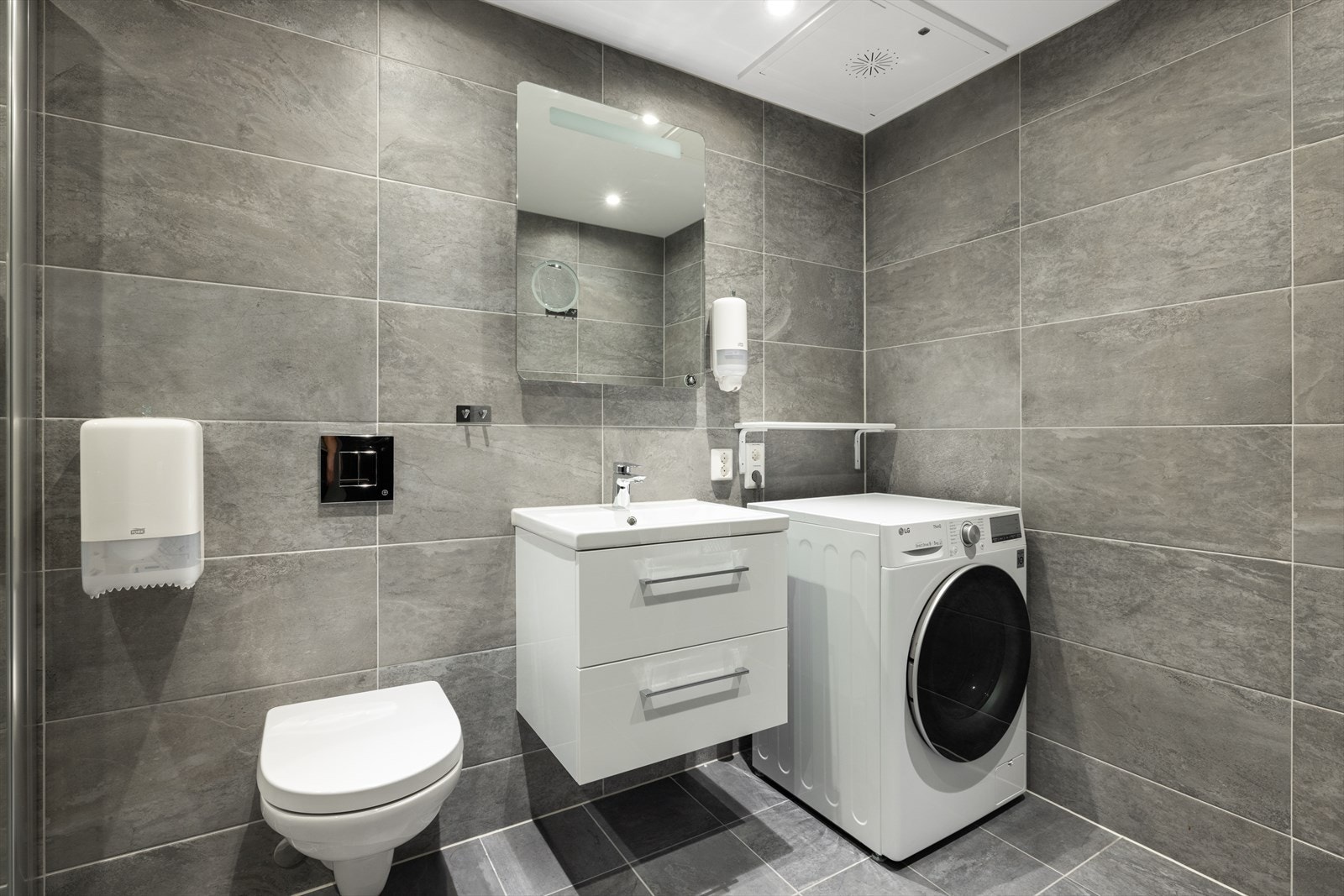 Flislagt bad innredet med servant på innredning, dusjhjørne og toalett. Galleribilde