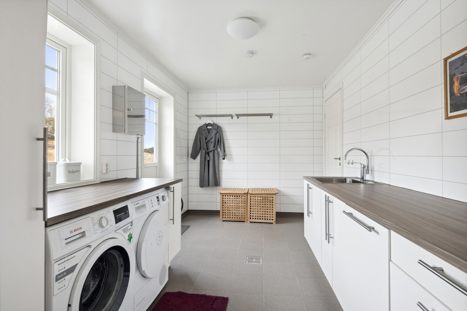 Stilrent vaskerom med flislagt gulv og mye benkeplass. Her har man også egen inngangsdør. Galleribilde