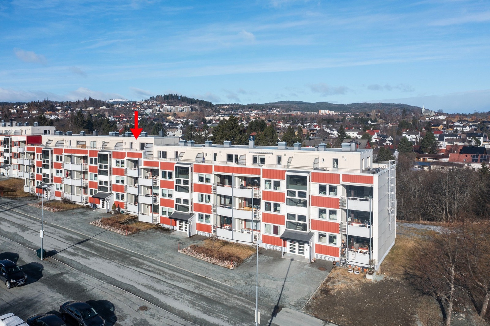 Dronefoto fasade og området bakenfor. Leilighetens plassering er markert med rød pil. Galleribilde