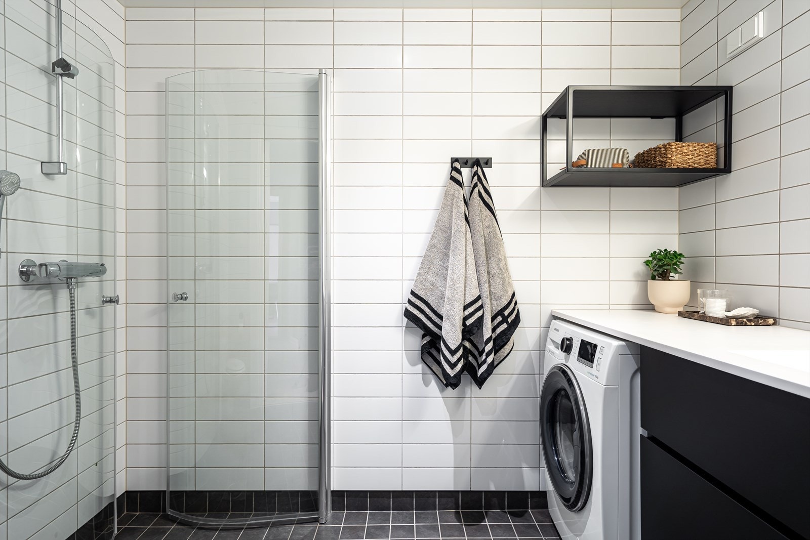 Baderommet har nøytrale fliser på vegger og gulv. Dusjhjørne med innfellbare glassvegger og vegghengt toalett. Galleribilde