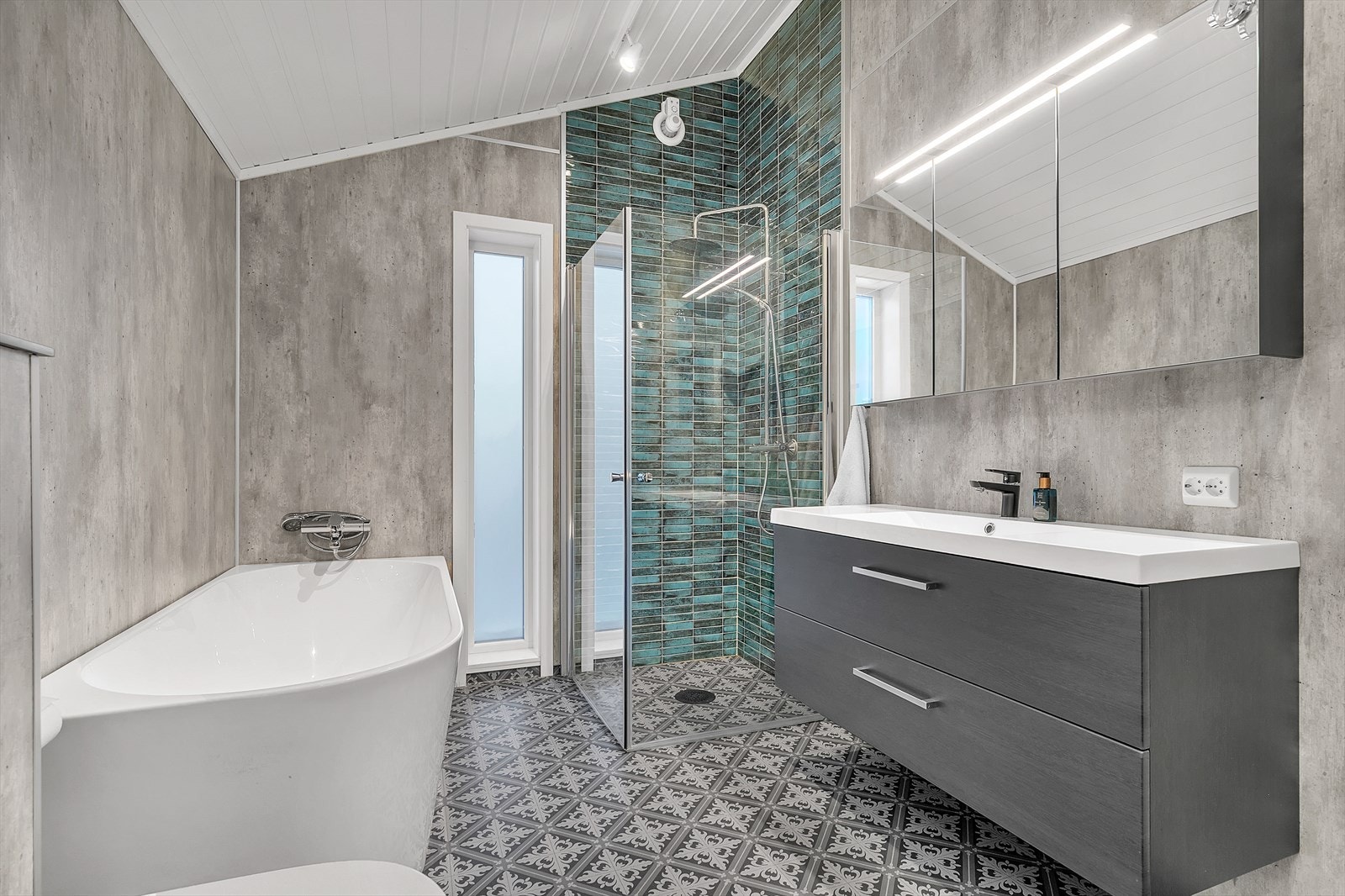 Badet er utstyrt med baderomsinnredning, vegghengt skap med skuffer, speilskap, dusjnisje, badekar og vegghengt toalett Galleribilde