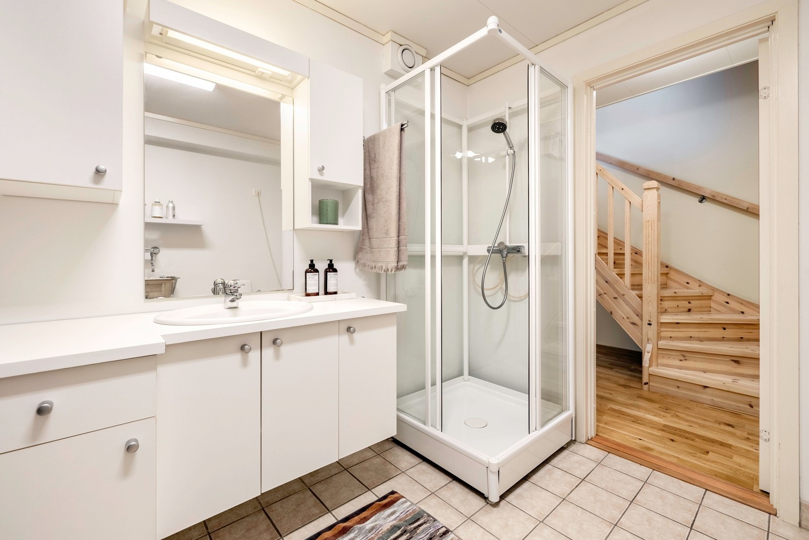 Badet nede er et kombinert bad/vaskerom med dusjkabinett, gulvvarme og utslagsvask i stål. Galleribilde