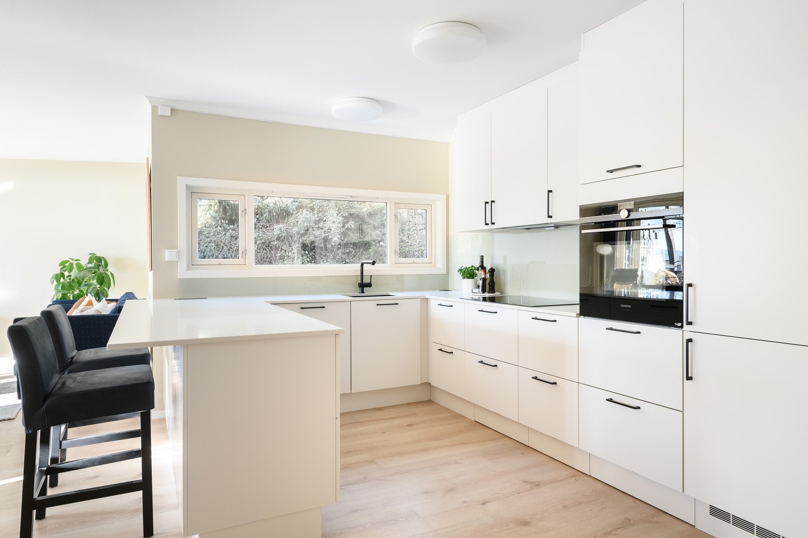 Topp moderne HTH-kjøkken fra 2022/23 med hvite fronter og lys kompositt benkeplate. Galleribilde