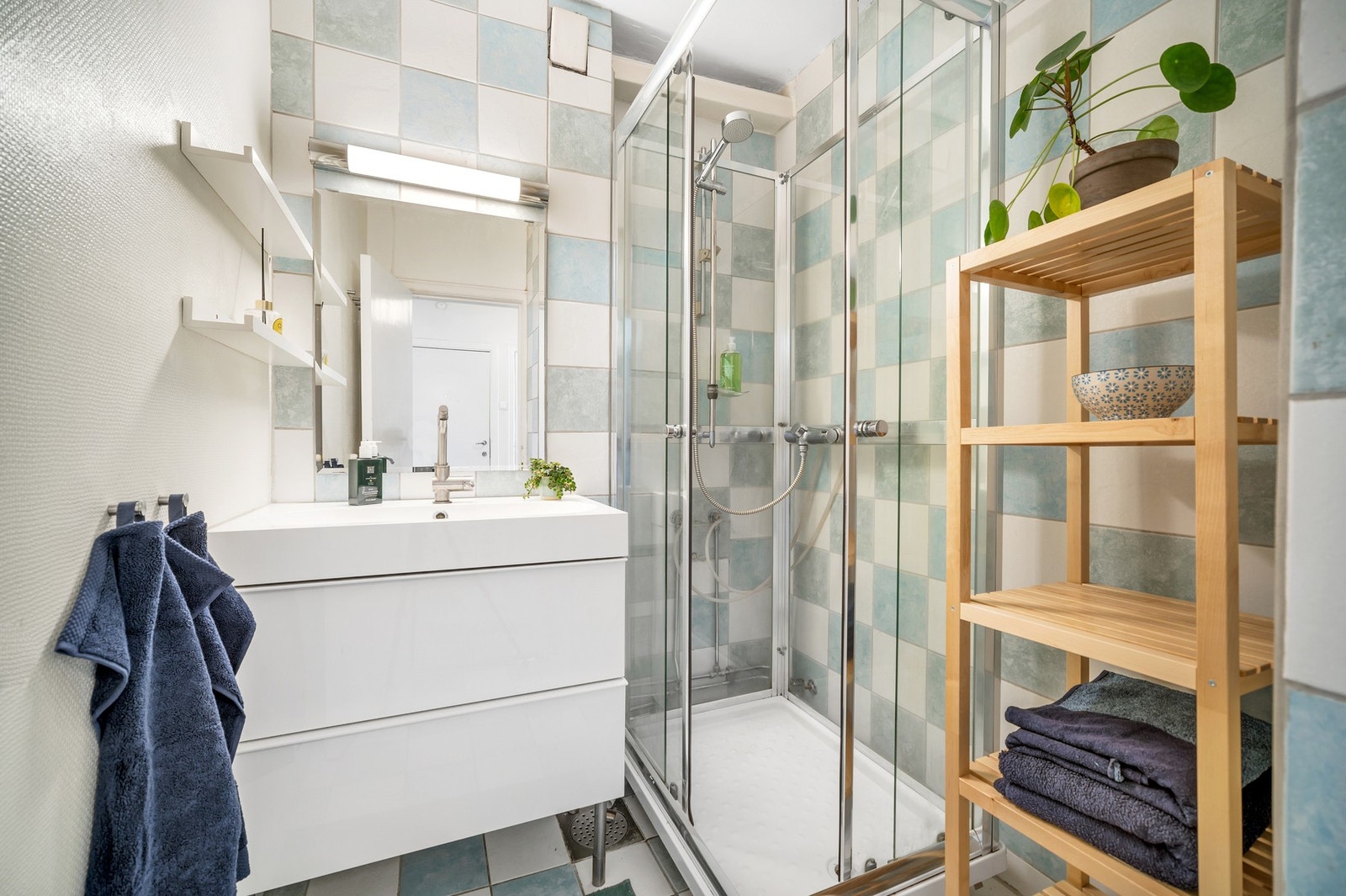 Lyst baderom med dusjkabinett, servant med underskap samt plass for oppbevaring. Galleribilde