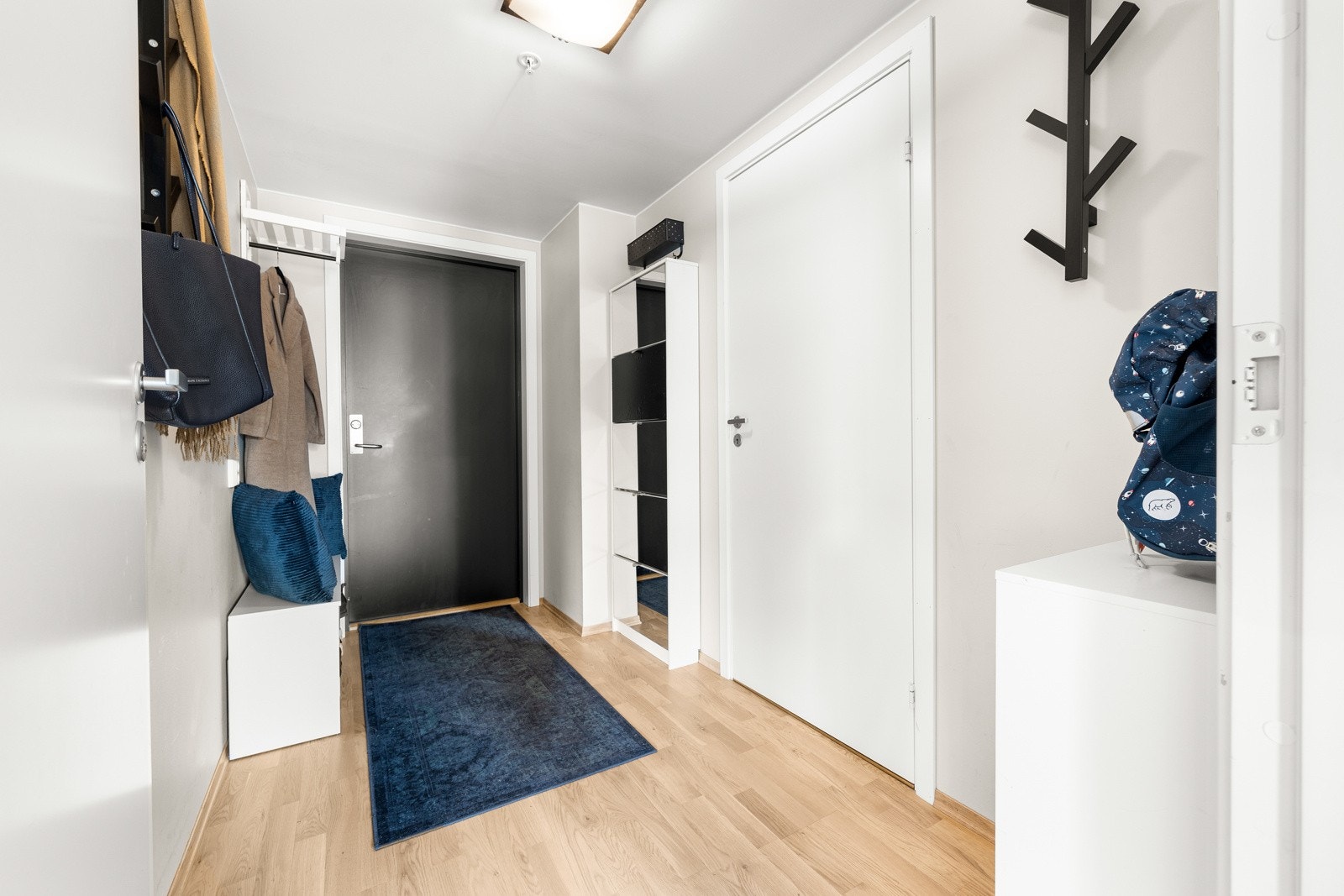 Inne i leiligheten kommer man inn i en lys og innbydende entré med åpen garderobeløsning Galleribilde
