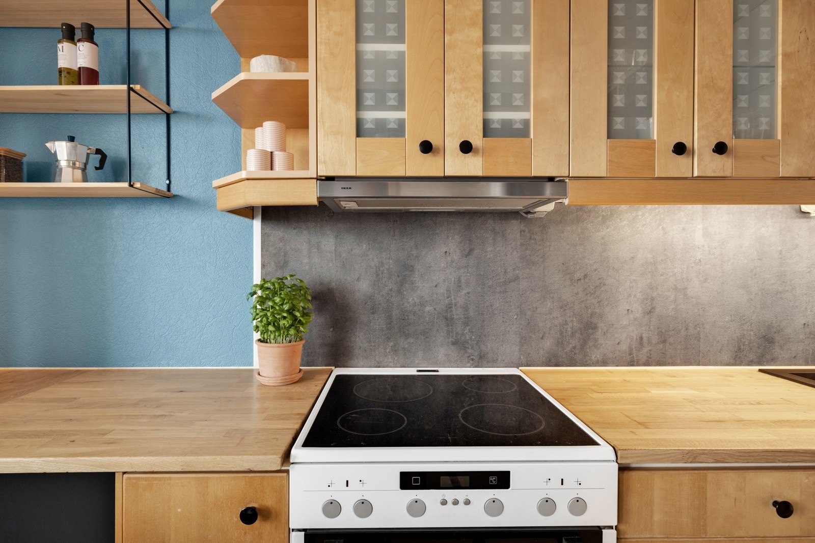 Over benken er det belysning og grå kitchen boards, og over kokesonen er det installert en ventilator med kullfilter Galleribilde
