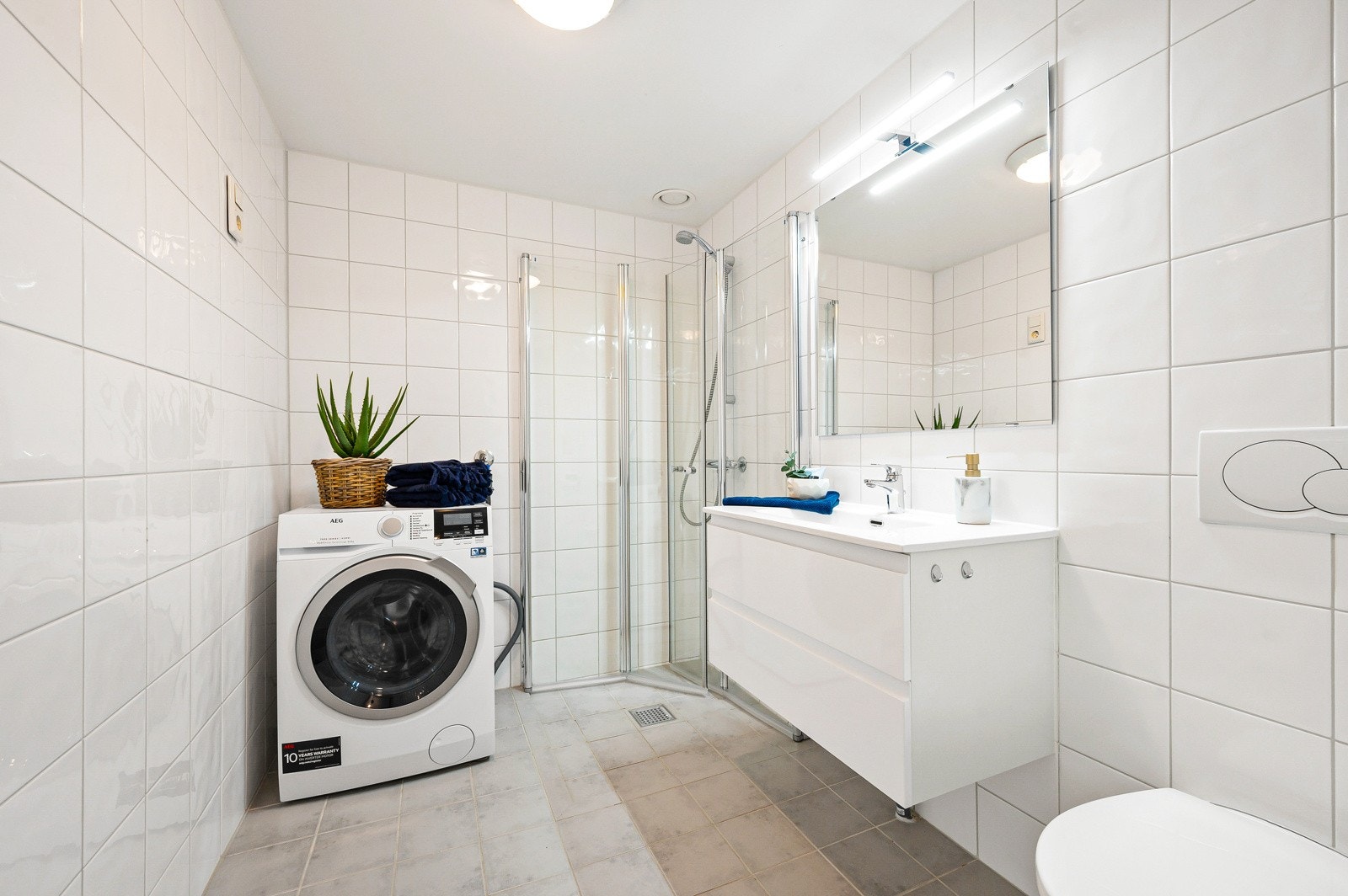 Badet er pent flislagt, har opplegg for vaskemaskin og plass til tørketrommel. Galleribilde