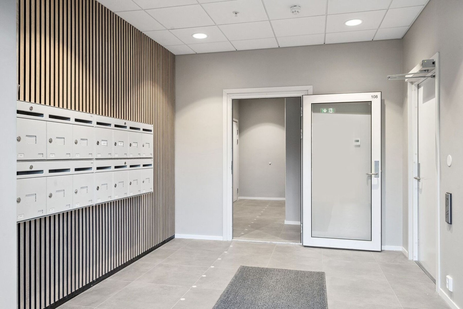 Gangen med postbokser på venstre side, garasje høyre side og trapperom med heis rett foran. Galleribilde