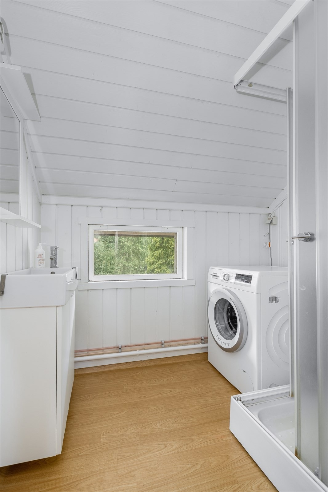 Badet er utstyrt med dusjkabinett og servantinnredning, samt opplegg for vaskemaskin. Galleribilde