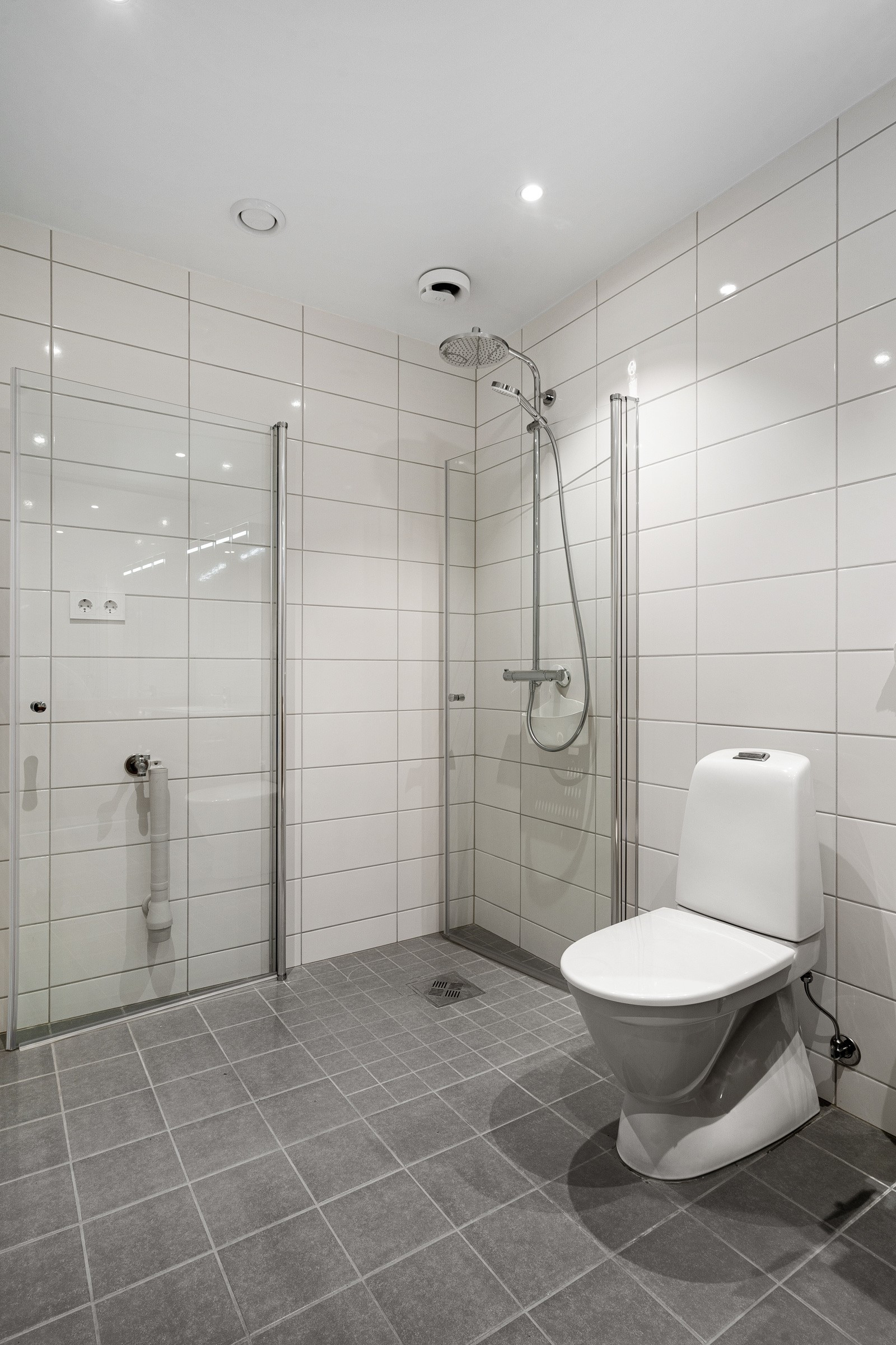 Badet fremstår lyst og stilrent, med opplegg for vask/trommel ved siden av dusjhjørnet.
