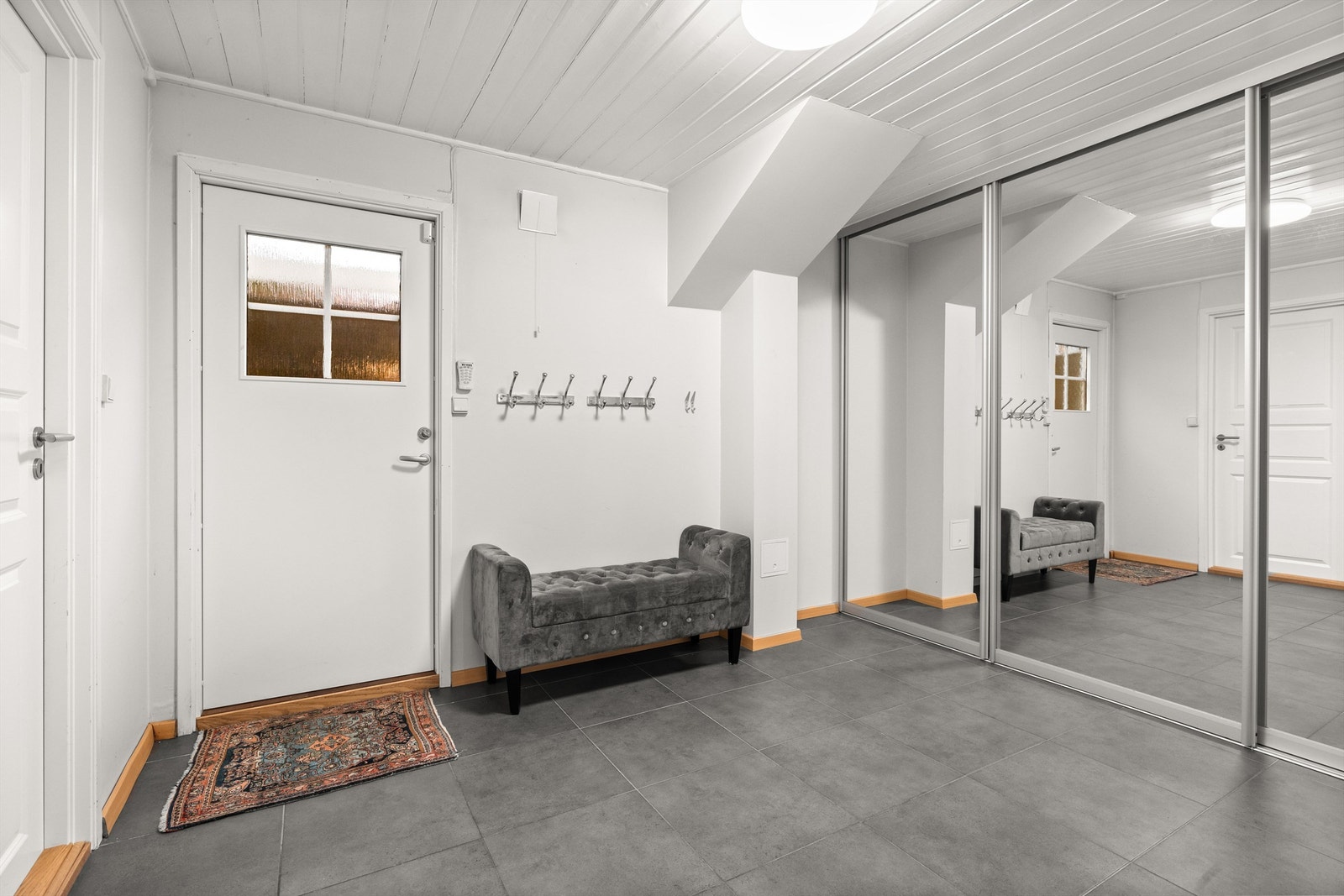 Fra den separate inngangen til underetasjen kommer man inn i en stor gang med fliser og varme i gulv Galleribilde