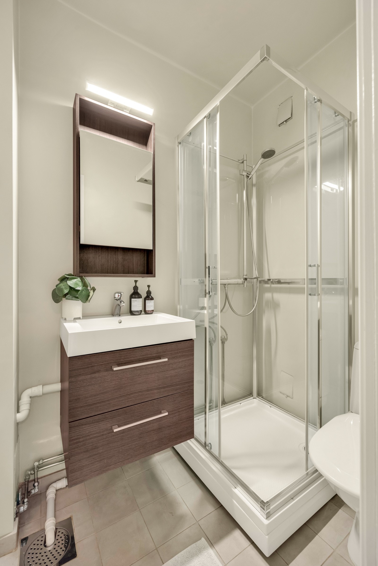 Flislagt gulv og glatte malte vegg/himlingsflater bestående av servantskap med glatte fronter og heldekkende servant Galleribilde