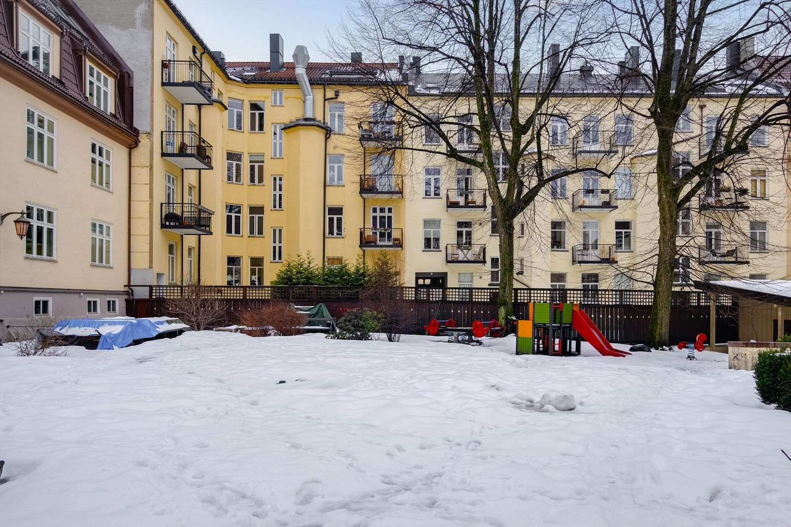 Pent opparbeidet bakgård med busker, trær, gressplen, belegningsstein og sittegrupper. Galleribilde