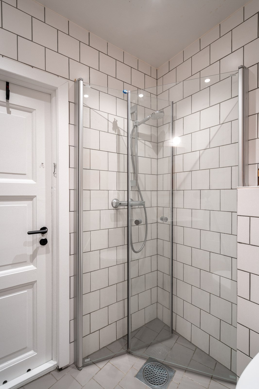 Badet er innredet med servantskap med glatte fronter og heldekkende servant, høyskap med glatte fronter, speil og lysarmatur på vegg over servant, veggmontert klosett og dusjhjørne. Galleribilde