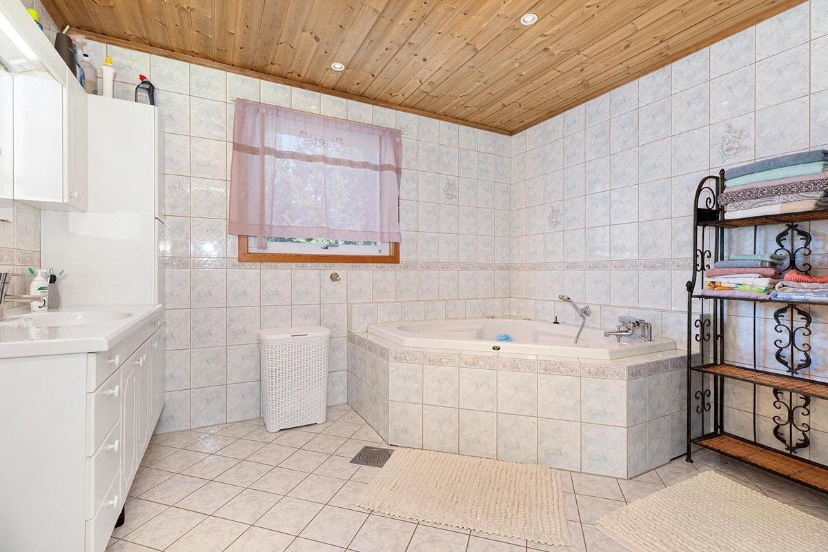 Romslig flislagt bad som byr på servant, innebygd badekar, dusjnisje med glassvegg og wc. Galleribilde