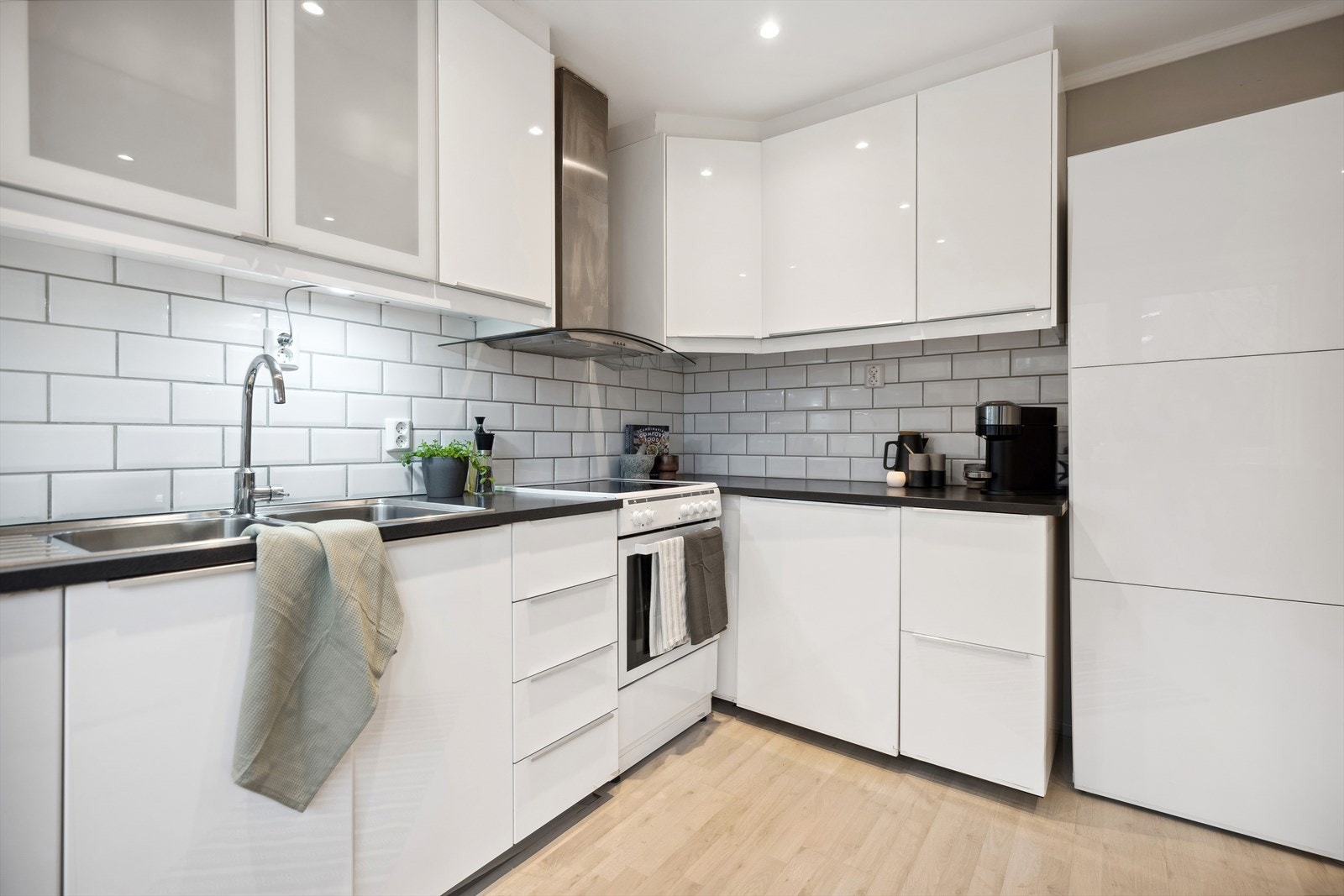 Innredningen består av glatte, høyglans fronter, samt noen vitrinedører og laminat benkeplate med nedfelt kum i rustfritt stål. Videre er det fliser på vegg over benkeplaten, og lys under overskap. Galleribilde