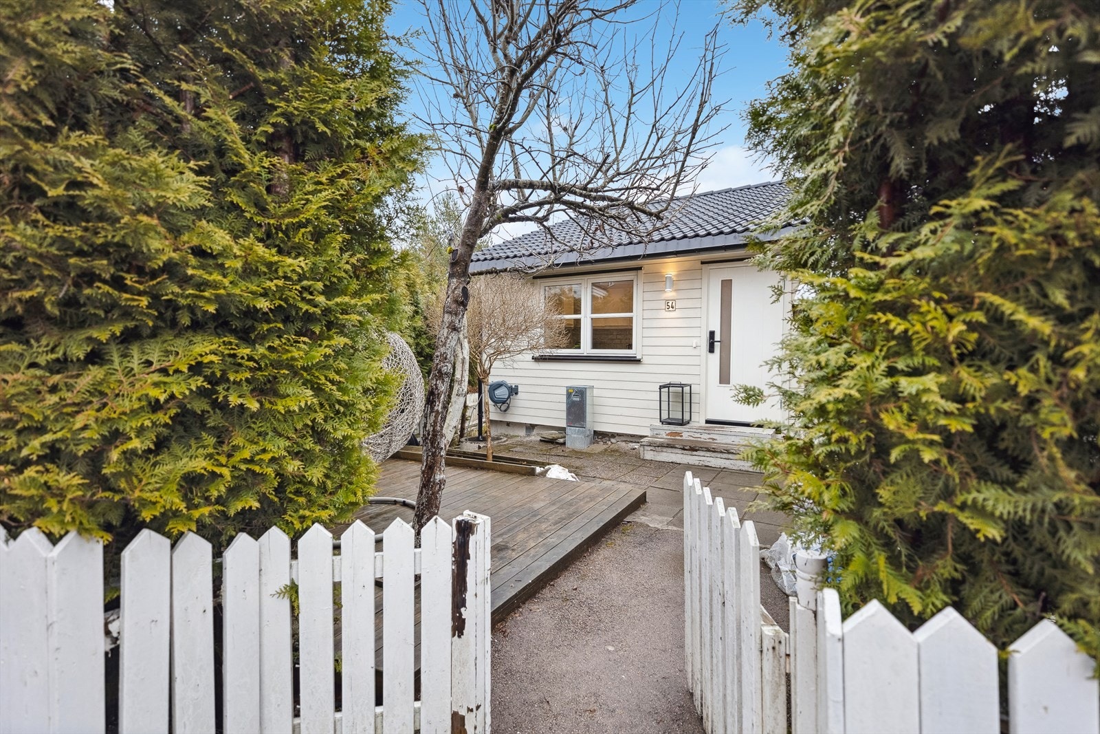 Inngangspartiet er opparbeidet med terrasseplatting, blomsterbed og steinheller. Galleribilde