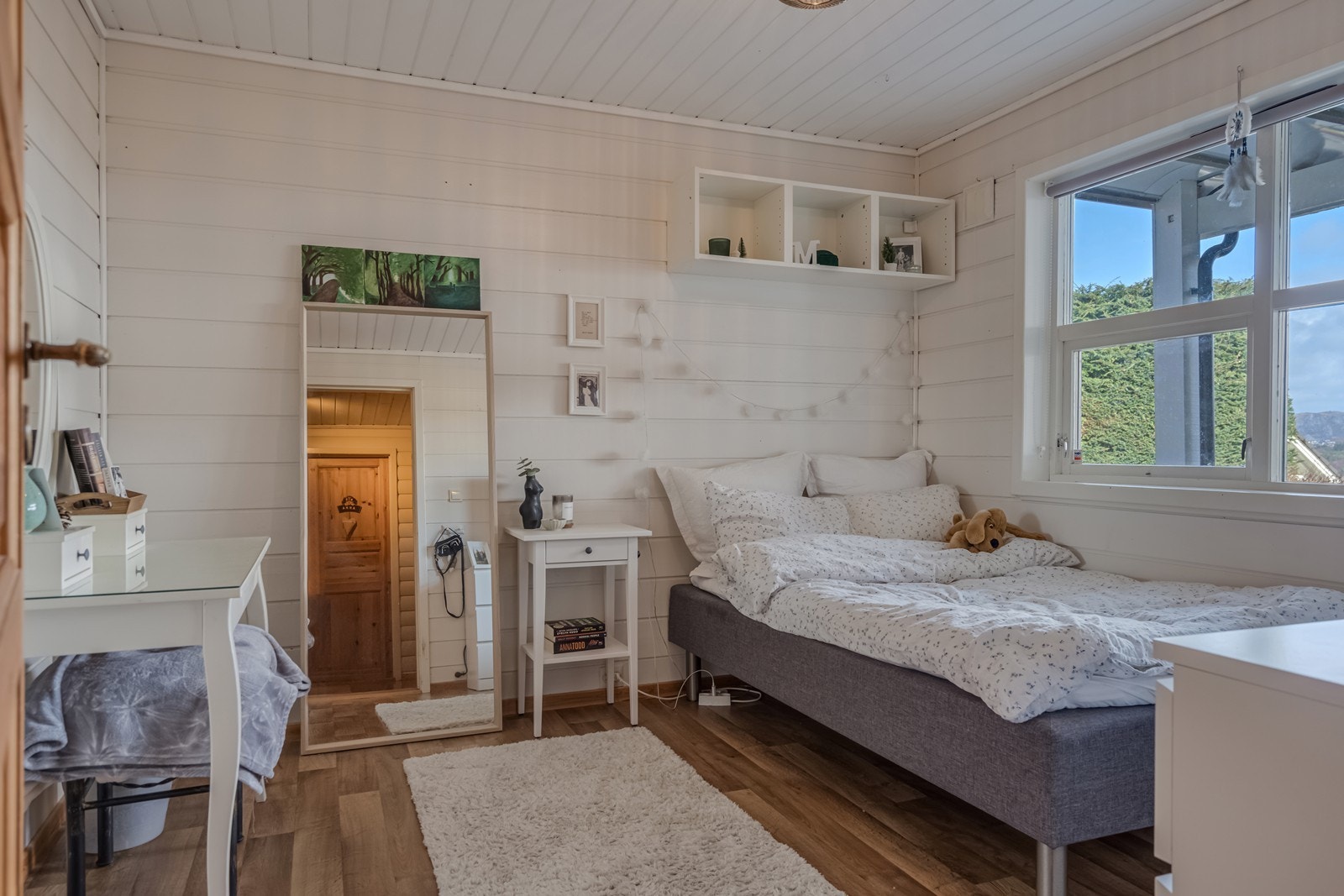 Soverom med belegg på gulv, lysmalt panel på vegger og ett dobbelt skap. Galleribilde