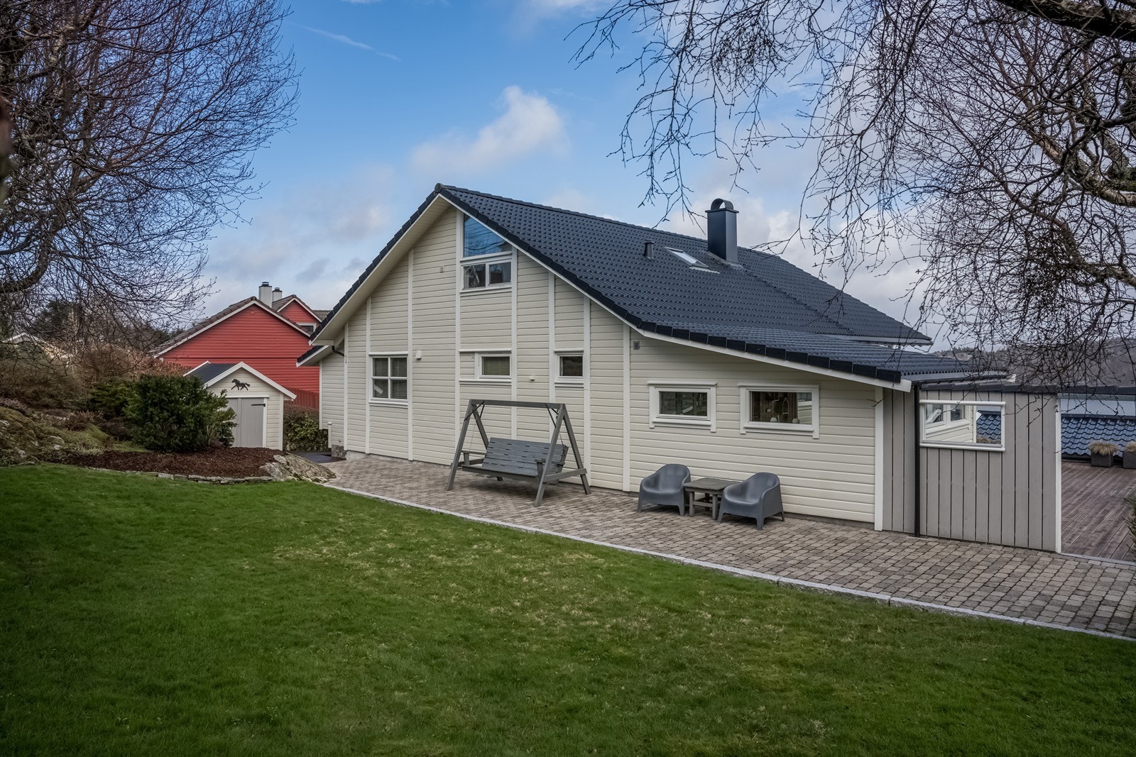 Hage på oppsiden av boligen med fine bedd, plen og vintergrønn beplantning. Det er også en frittstående bod med lagerplass i hagen. Boda har sidevindu, doble lemdører i front og støpt gulv. Galleribilde