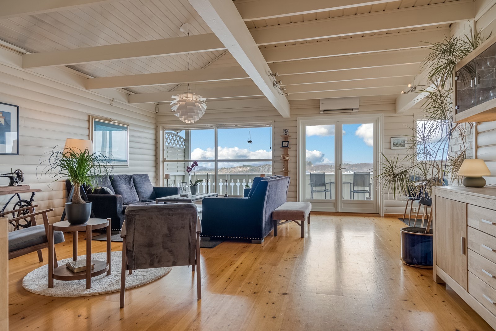 Utgang via doble dører til romslig og overbygget terrasse mot fjordutsikten. Åpen løsning og svært god takhøyde opp til hems/loft. Galleribilde