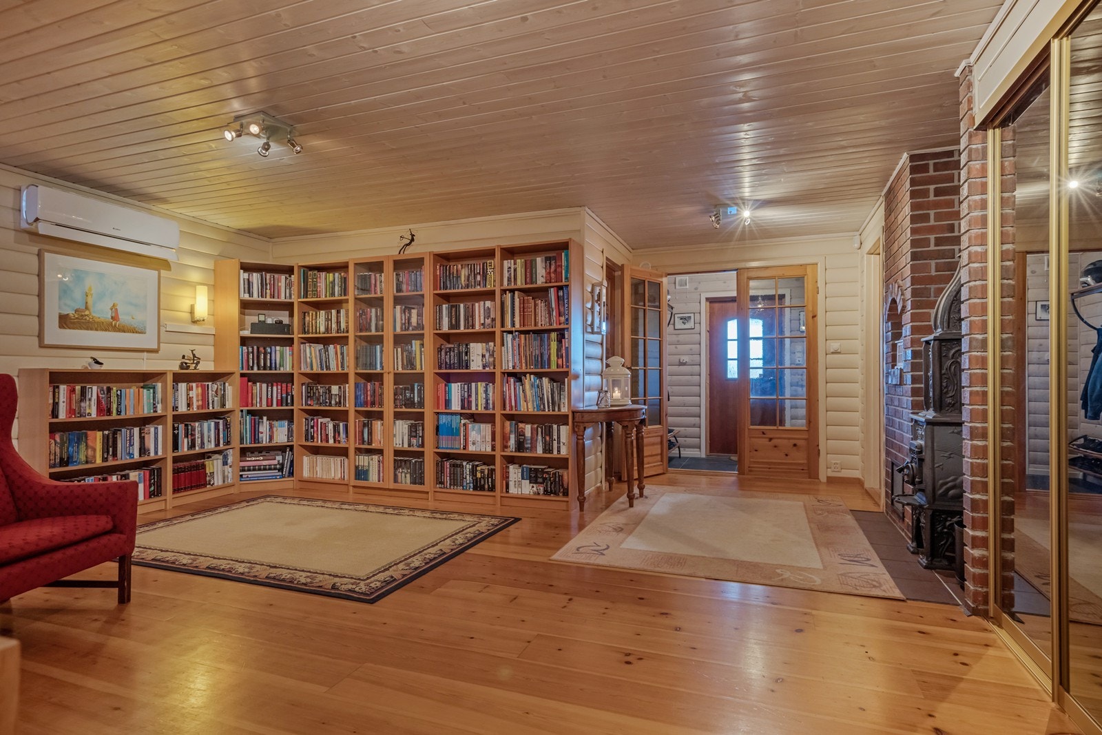 Inngang til gang med steinfliser på gulv, varmekabler og hvitbeiset rundtømmerpanel på vegger. Stort innebygget skap her. Dobbel glassdør inn til romslig hall m/ heltre gulv, vedovn fra Ulefos, varmepumpe og skyvedørsgarderobe med speilfronter. Galleribilde