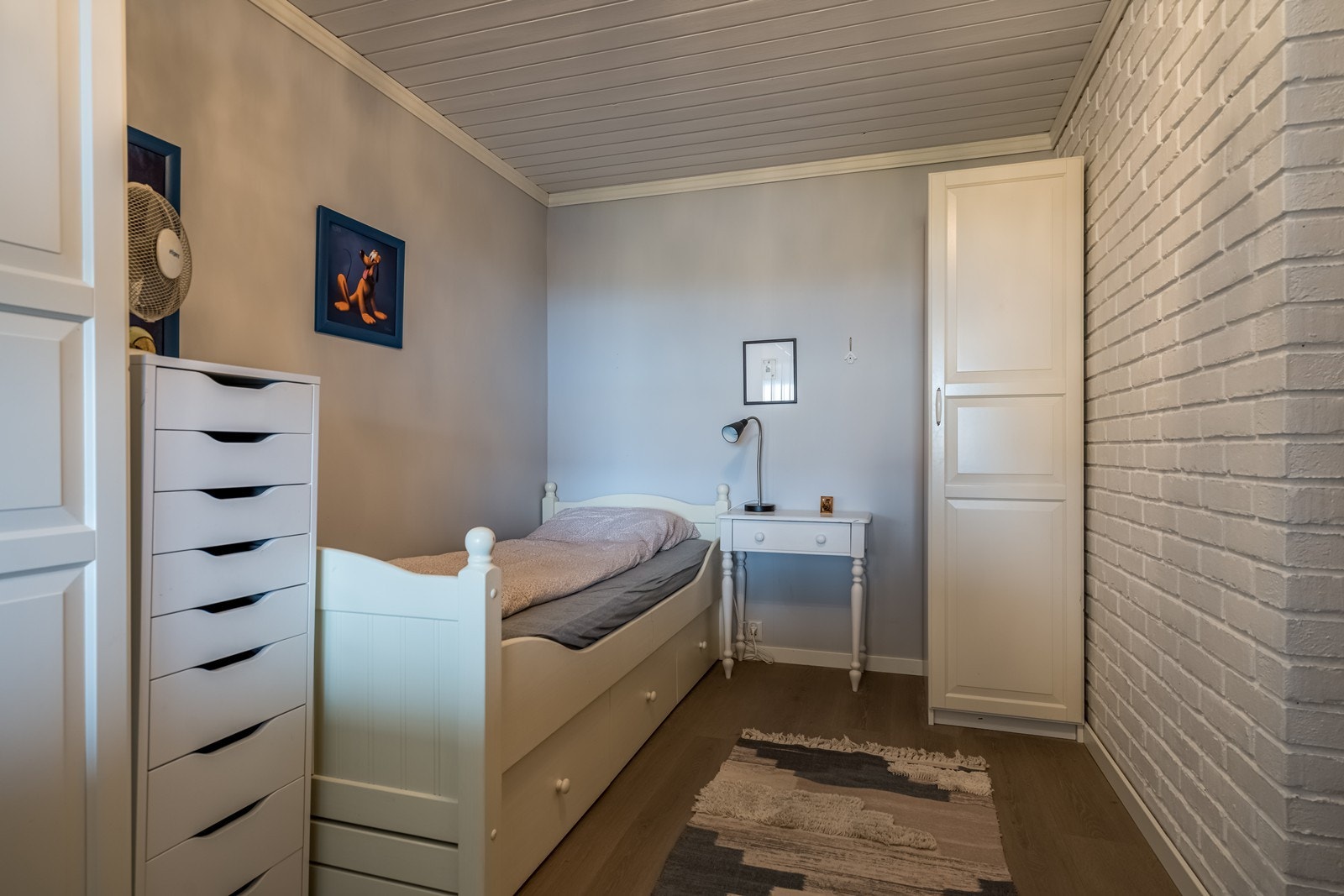 Soverom med en stavs laminatgulv, panelovn, to doble garderobeskap og ett enkelt garderobeskap. Malt tapet på vegger. Galleribilde