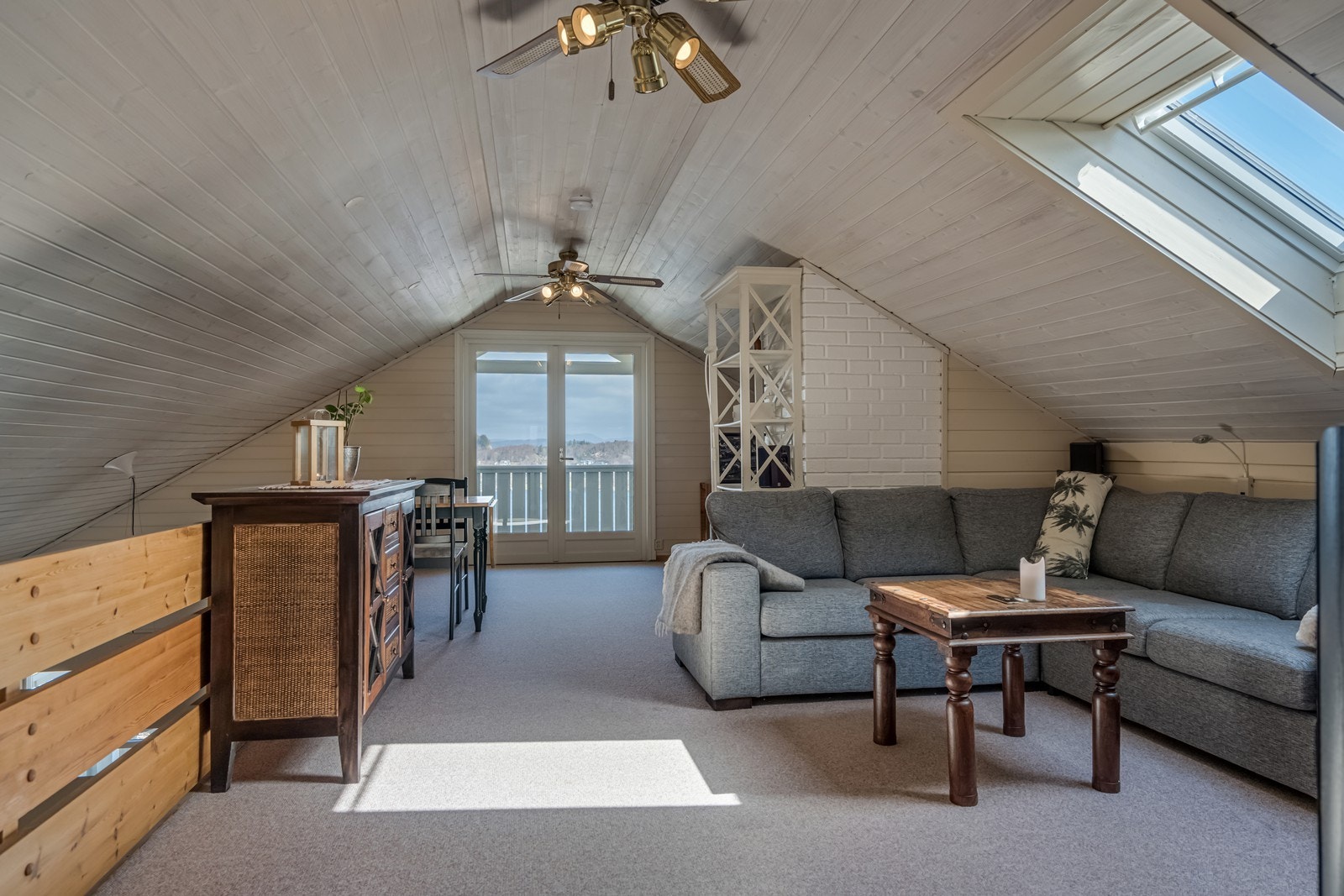 Lakkert furutrapp opp til loftstue med teppe på gulv, takvindu, utgang via doble dører til overbygget balkong skjermet for både vind og innsyn samt har nydelig og vidstrakt utsikt. Galleribilde