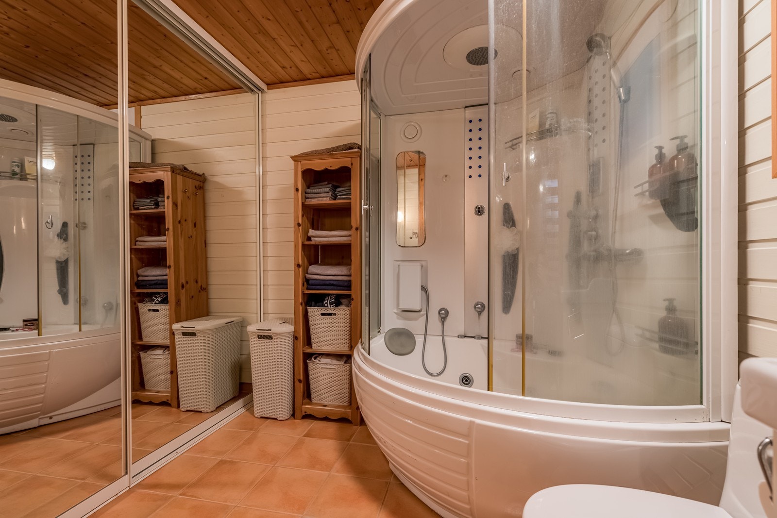 Bad med fliser og varmekabler på gulv, baederomsinnredning, wc, stor skyvedørsinnredning med innredning og speilfronter. Stort kombinert badekar og dusj med stereoanlegg, boblebad funksjon, steam funksjon og regnvannsdusj. Galleribilde