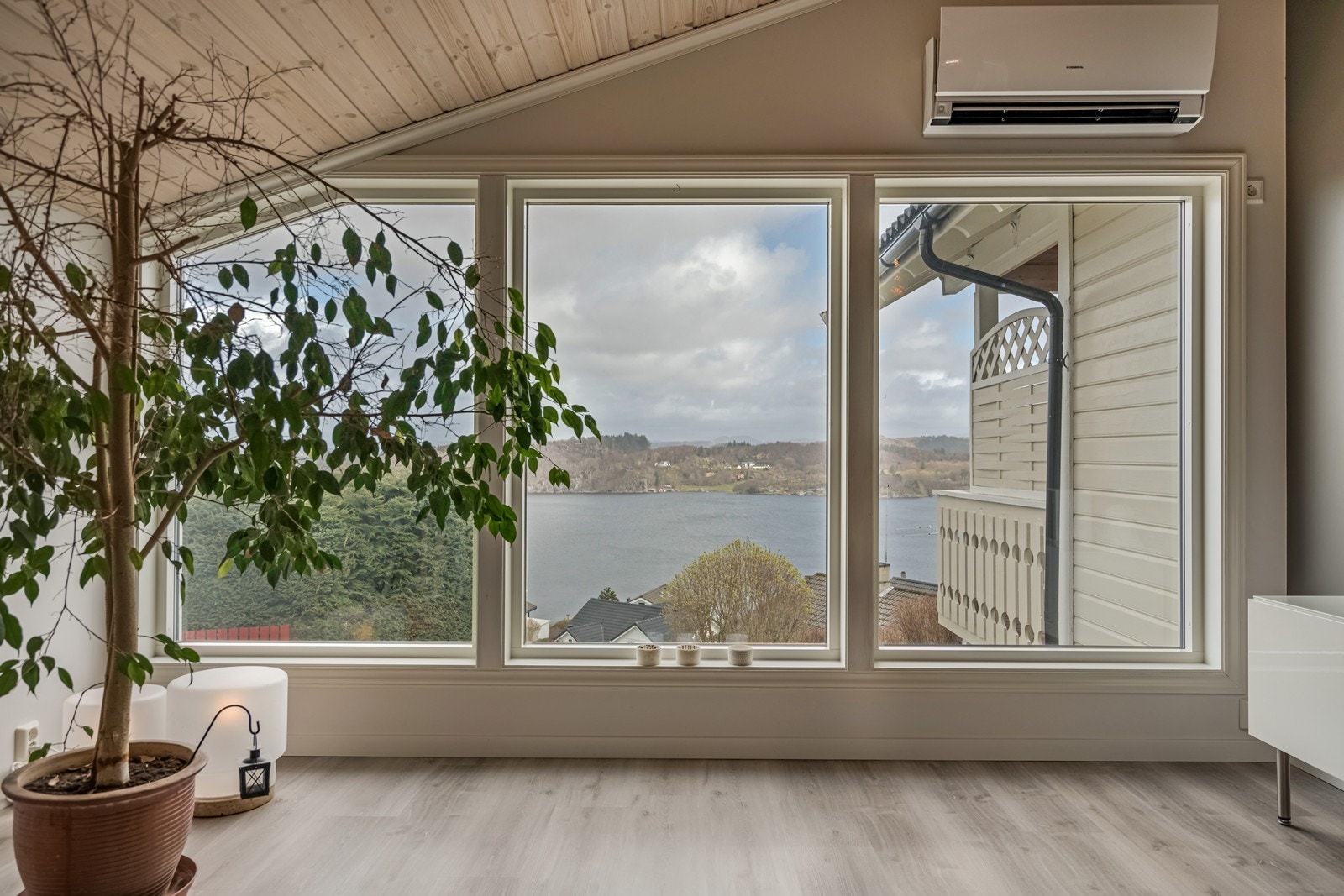 Påbygget (2015) stue mot nord med inngang direkte fra hovedstua. Her er det varmepumpe, laminatgulv, store vinduer mot fjordutsikten, skråtak med god takhøyde, fastmontert trippel kontorplass med skuffer og fastmontert seksjon. Galleribilde