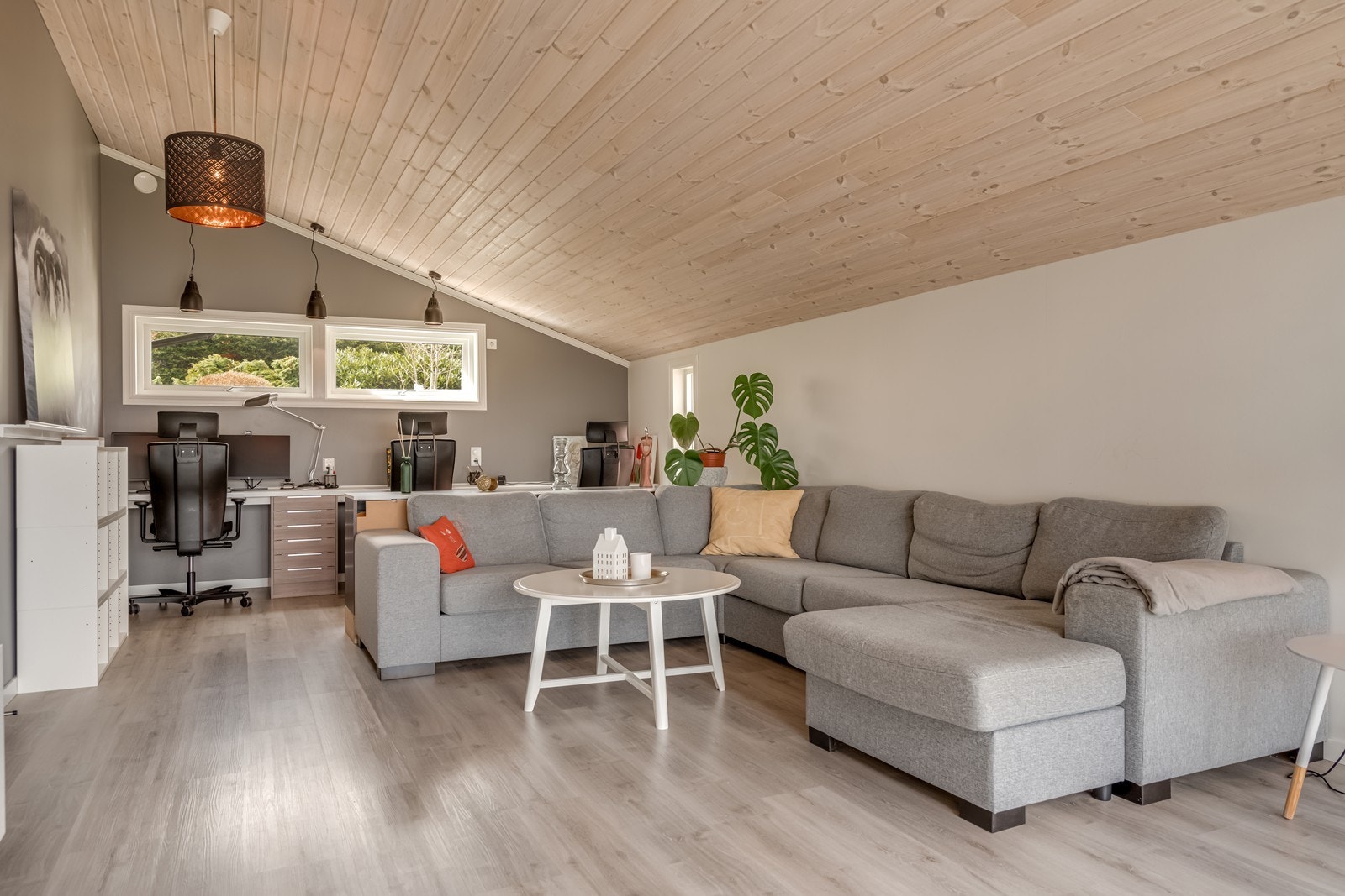 Påbygget (2015) stue mot nord med inngang direkte fra hovedstua. Her er det varmepumpe, laminatgulv, store vinduer mot fjordutsikten, skråtak med god takhøyde, fastmontert trippel kontorplass med skuffer og fastmontert seksjon. Galleribilde