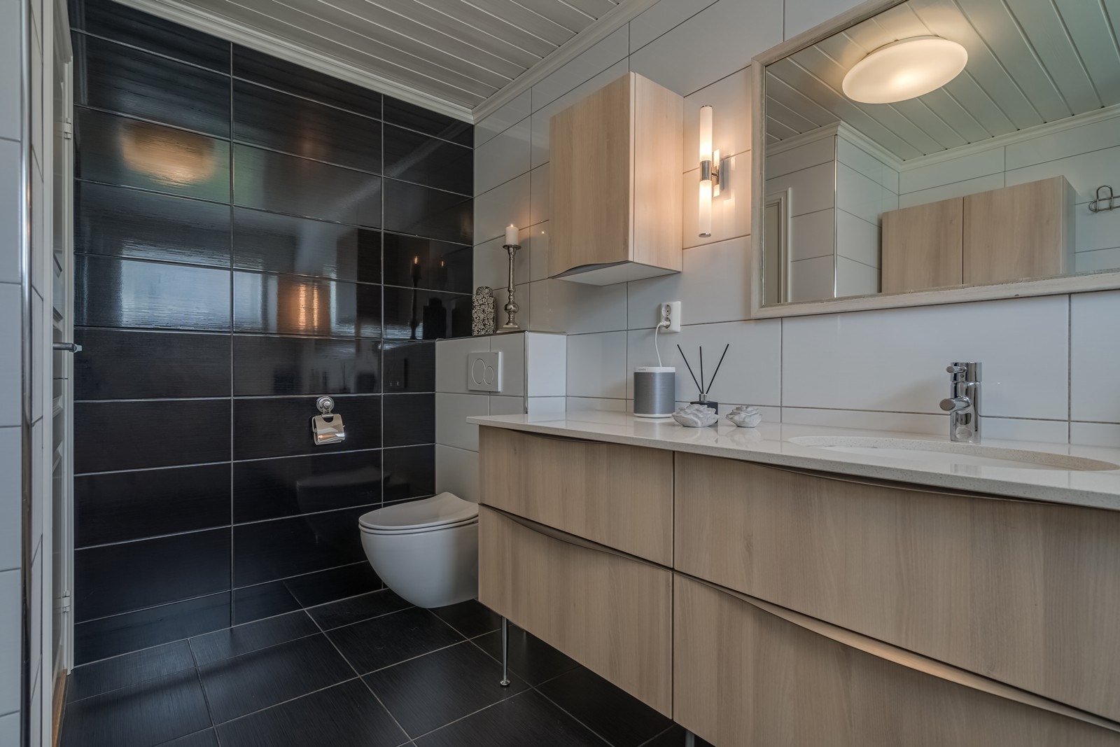 Flislagt bad med varmekabler, vegghengt toalett, samsonite benkeplate fra Skattkjær med underlimt vask, seks underskuffer, stor benkeplate, stort speil og belysning, et ekstra skap med seks skapdører og dusjkabinett med regnvannsdusj. Galleribilde