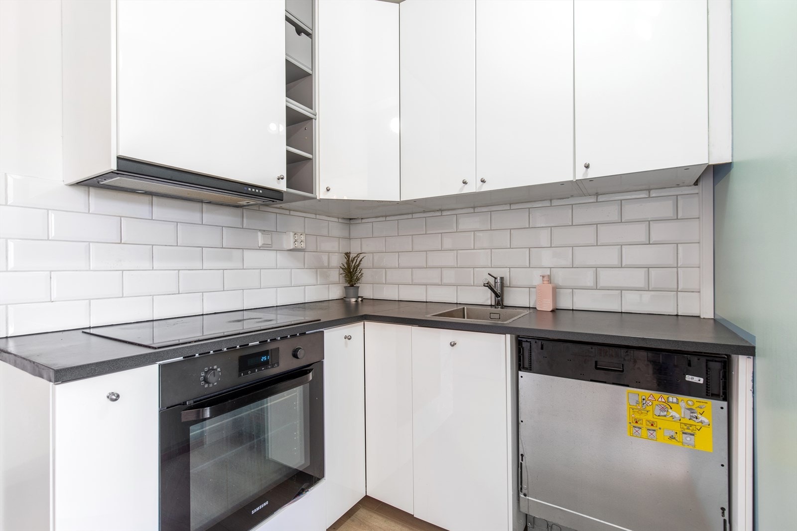 Kjøkkenet har innredning med glatte fronter og benkeplaten er av laminat. Det er integrerte hvitevarer som komfyr, platetopp og opplegg for oppvaskmaskin. Galleribilde