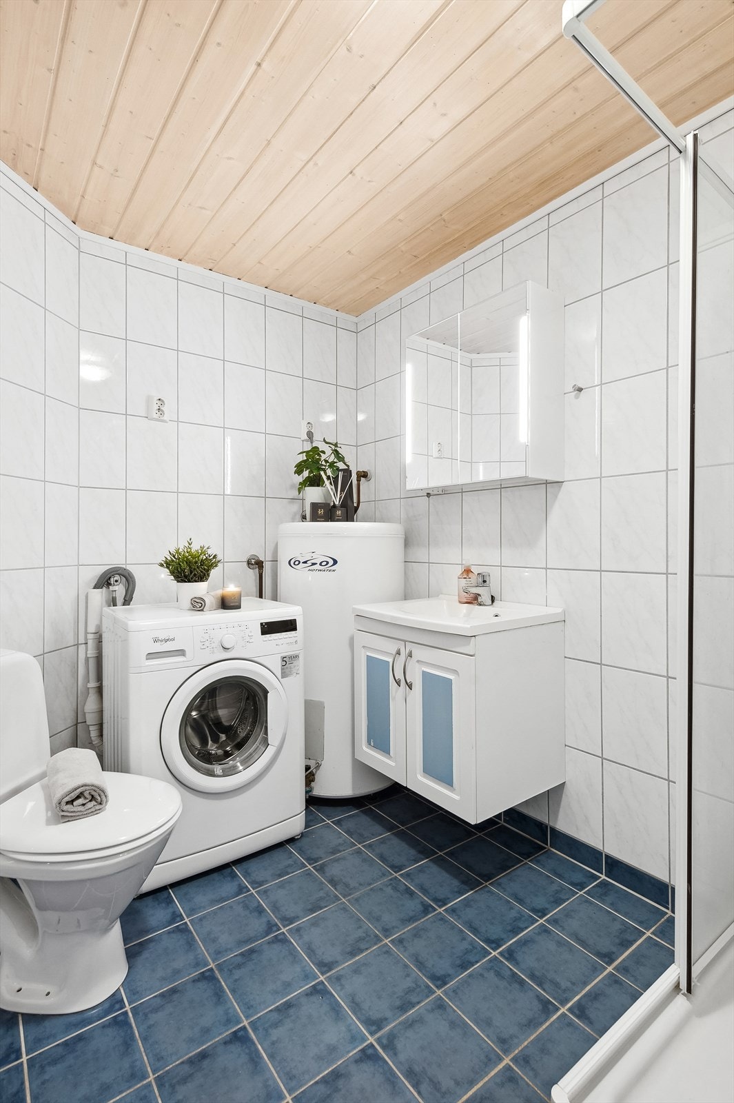 Baderom i underetasjen har hvite fliser på veggene og blå fliser på gulvet. Det er elektriske varmekabler i gulvet. Galleribilde