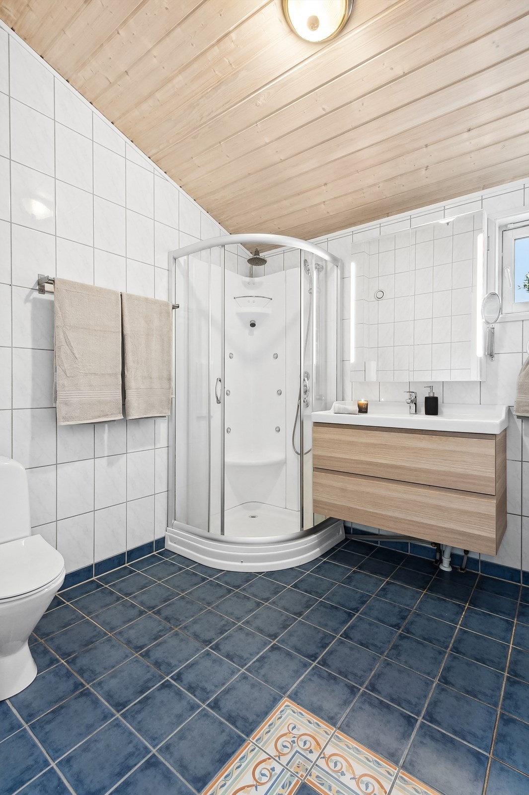 Baderommet i hovedetasjem har hvite keramiske fliser på veggene og blå fliser på gulvet. Galleribilde