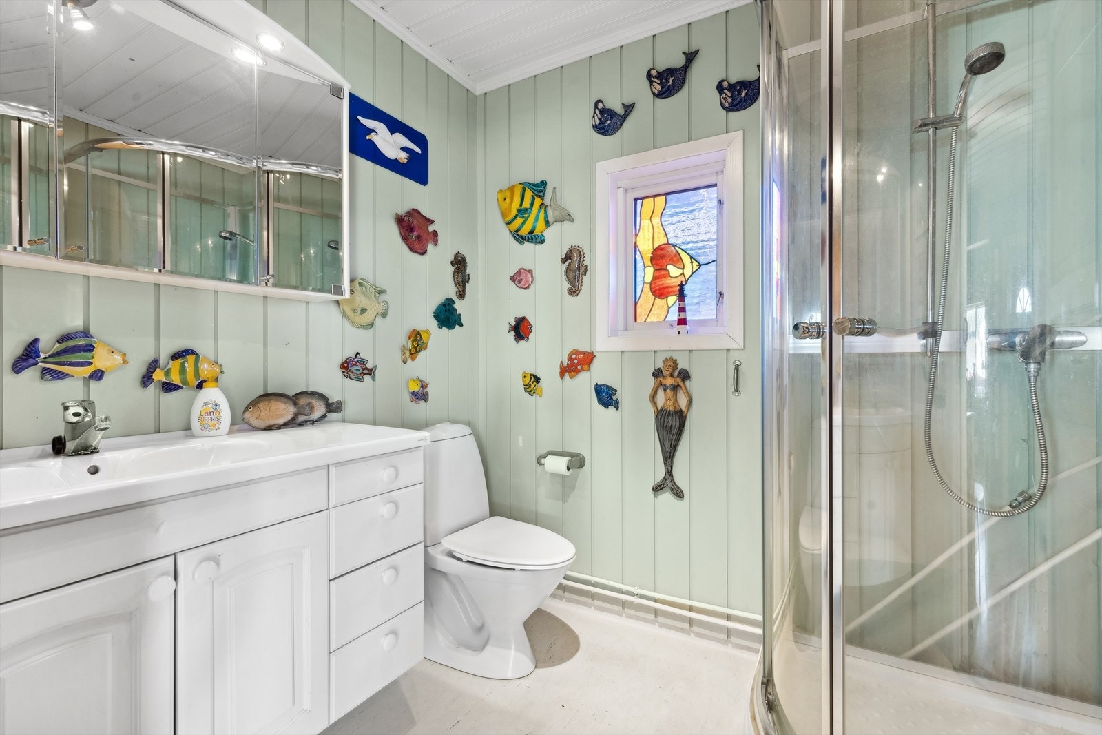 Badet er utstyrt med et dusjkabinett, lys innredning med heldekkende servant, speilskap med overliggende belysning og toalett. Galleribilde