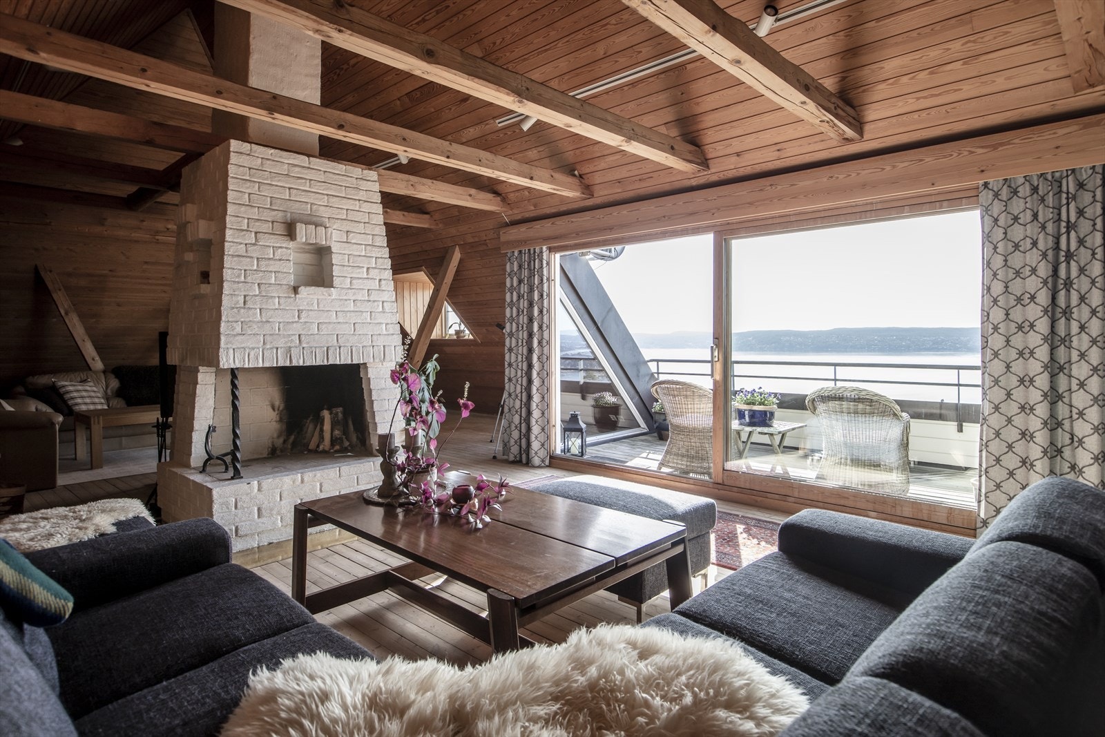 Loftstue med peis, vedovn og utgang til inntrukket terrasse Galleribilde