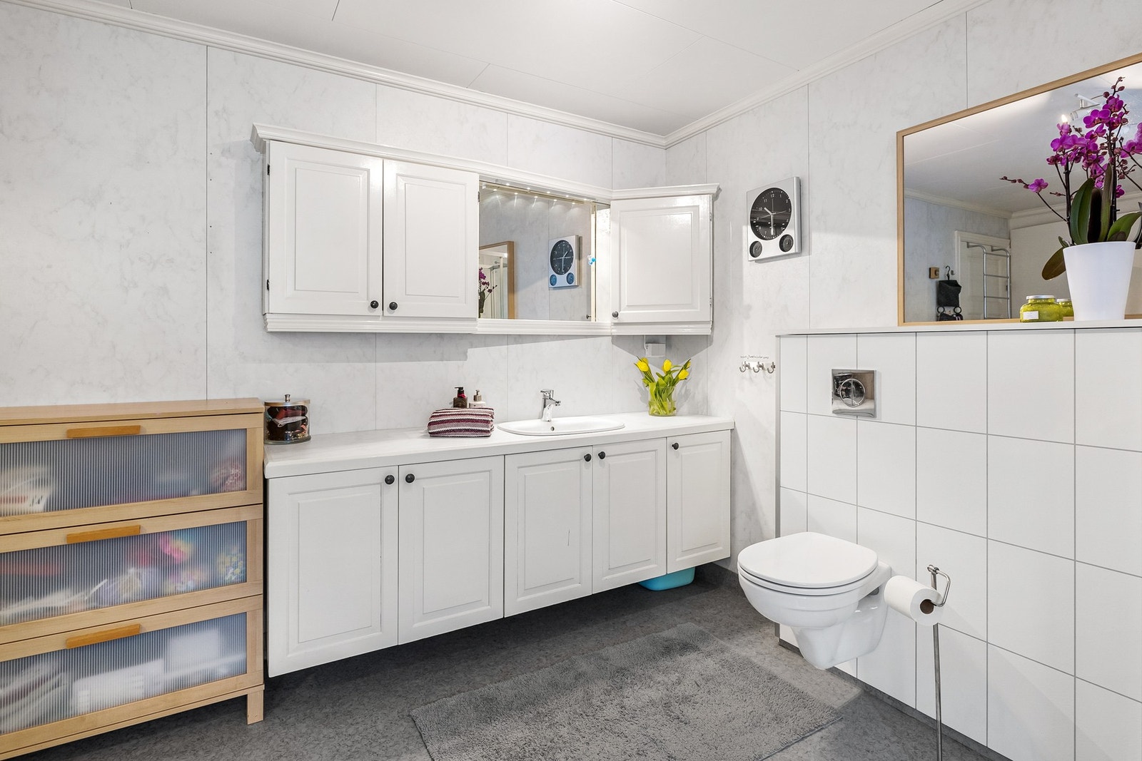 Badet har innredning med nedfelt servant, veggmontert toalett og dusjkabinett Galleribilde