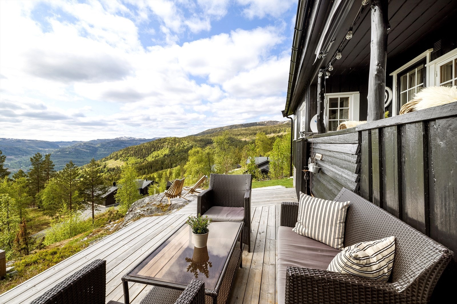 Det er overbygget balkong ut fra stuen med trapp ned til en annen terrasseplatting. Galleribilde