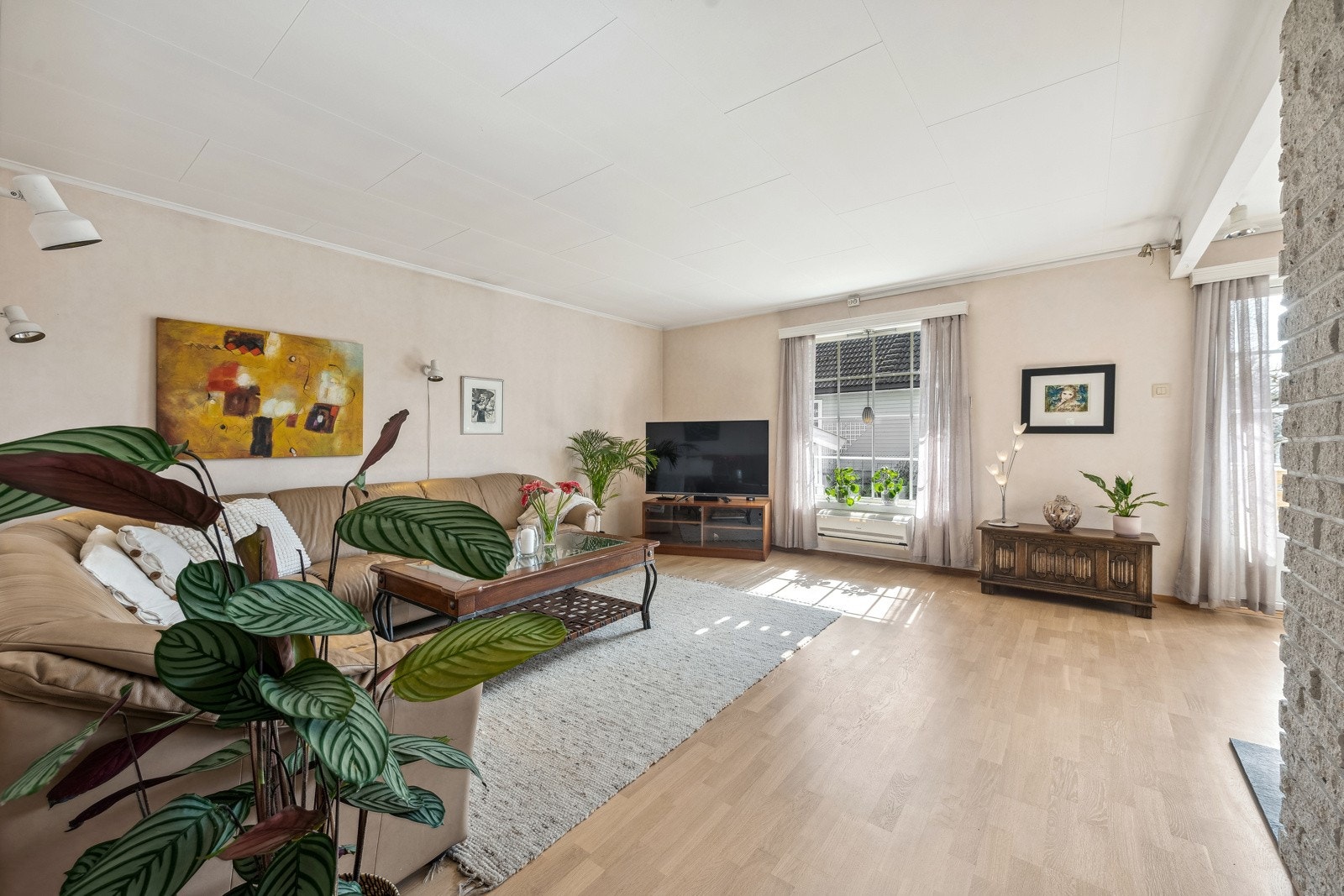 Åpen stue med store vindusflater på 2 sider og dør ut mot terrasse og hage. Galleribilde