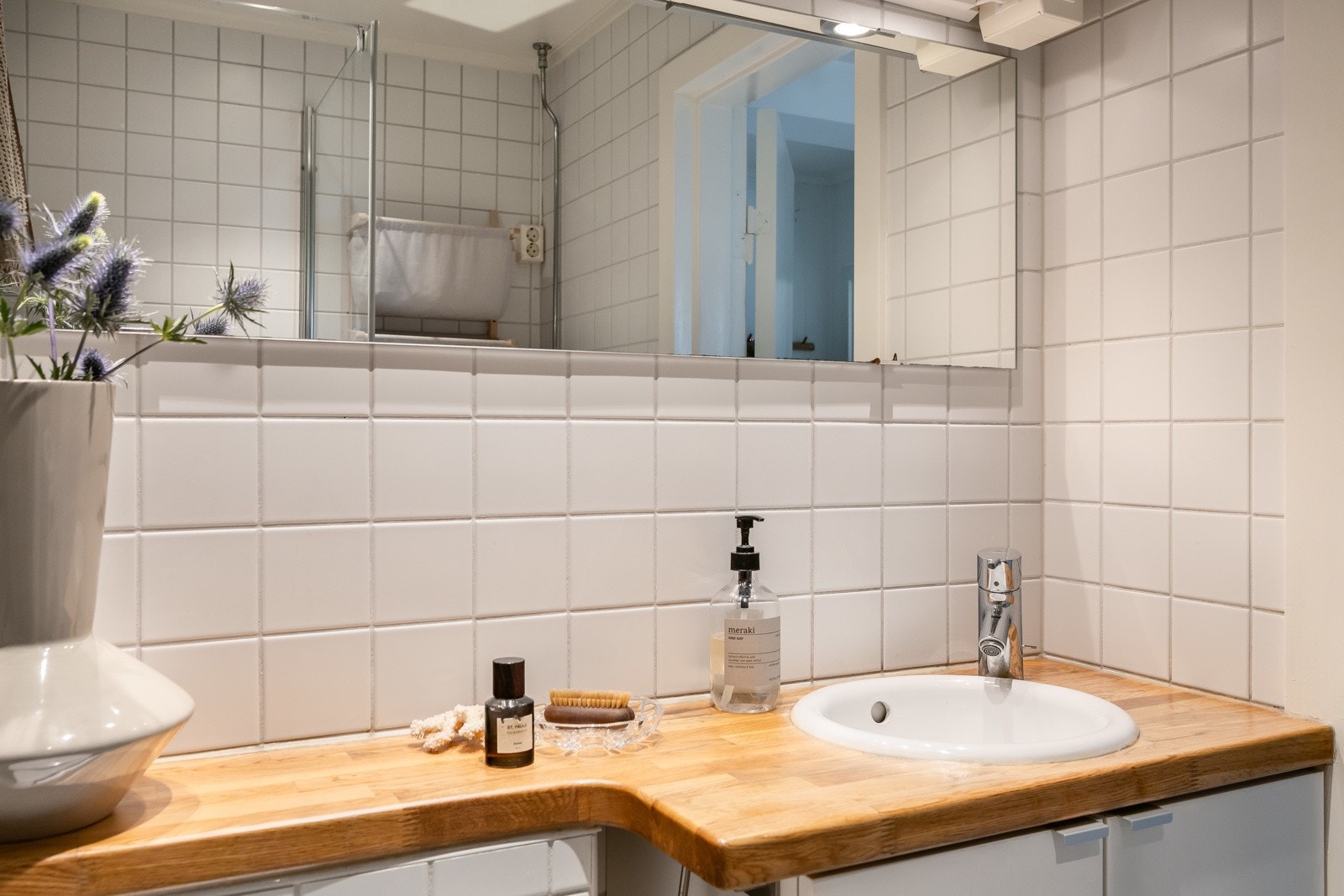 Badet har opplegg for vaskemaskin og servant nedfelt i heltre benkeplate. Galleribilde