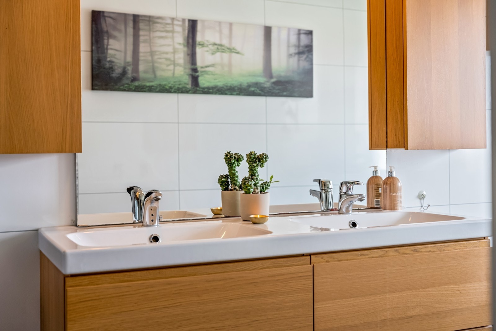 Bad 1. etg. med fliser og varmekabler på gulv, baderomsplater på vegger, dusjkabinett med regnvannsdusj, wc, baderomsinnredning med dobbel servant, fire underskuffer, dobbelt speilskap, stort fastmontert speil, badekar og nydelig fjordutsikt. Galleribilde