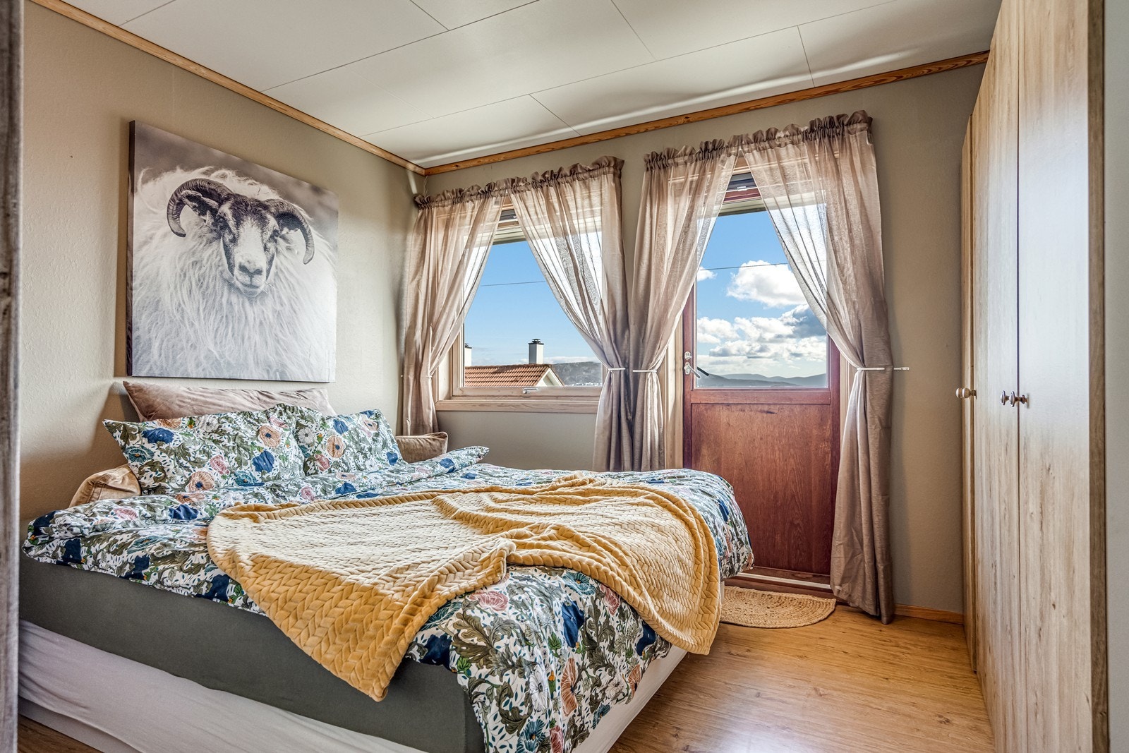 Dobbelt soverom med laminatgulv, tapetserte vegger, plissê gardiner både i vindu og i balkongdør ut mot overbygget balkong med nydelig fjordutsikt. To doble garderobeskap. Galleribilde