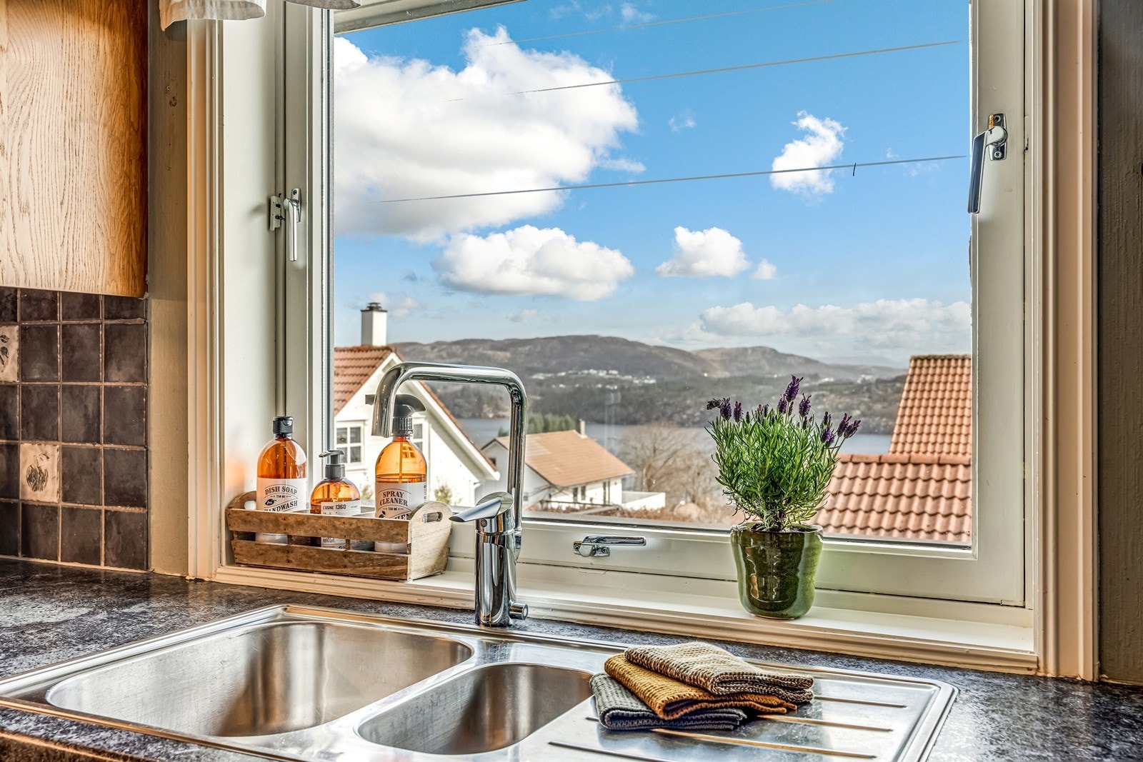 Stor laminatbenkeplate med keramisk koketopp og halvannen nedfelt vask. Integrerte hvitevarer som oppvaskmaskin, int. micro og int. stekeovn. Galleribilde