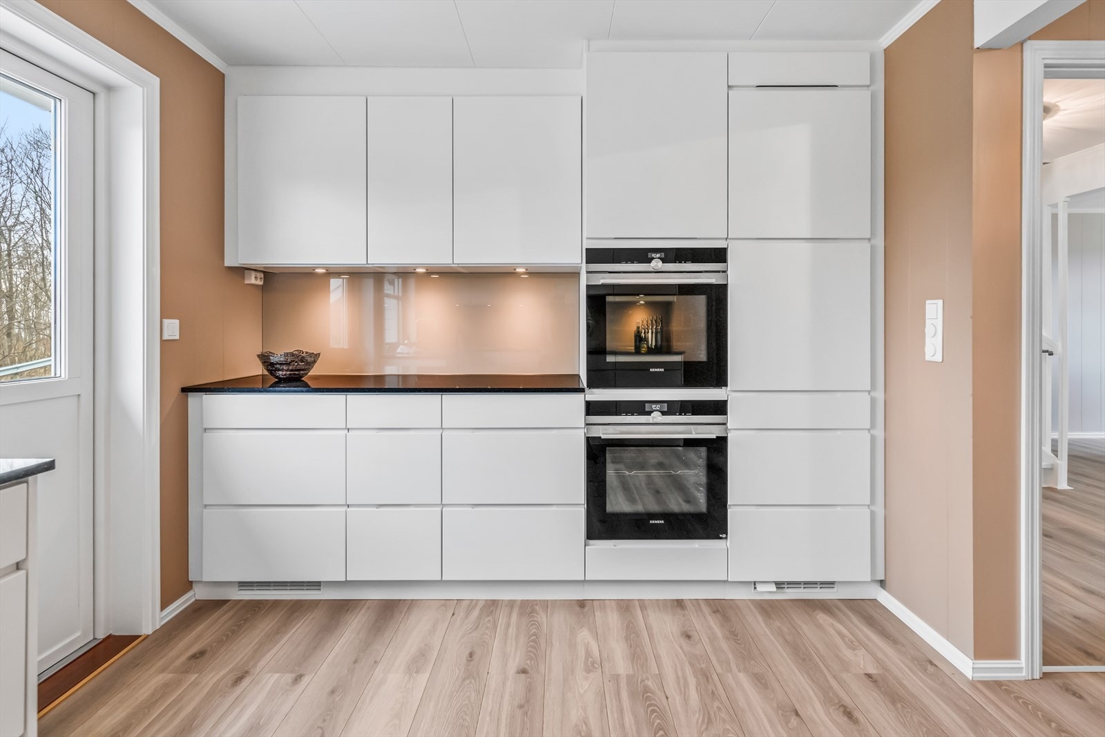 Hvitevarene er integrert i innredningen, bestående av koketopp, kjøleskap, oppvaskmaskin og to stekeovner i høyskap. Galleribilde